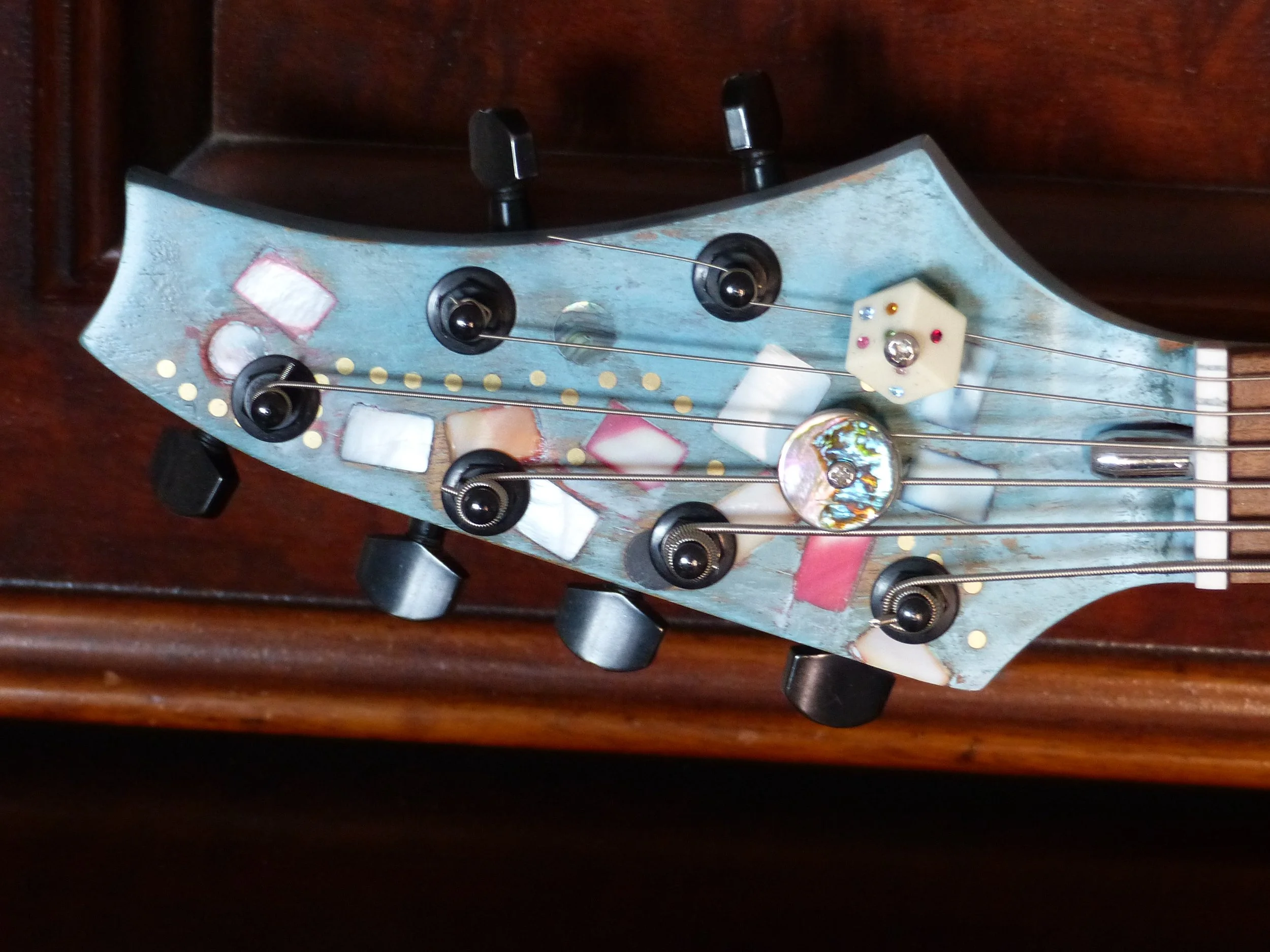 headstock of 6 string bass guitar, custom made, party theme, inlay mother of pearl and abalone. Immortal Guitars, luthier Mike Moulton.