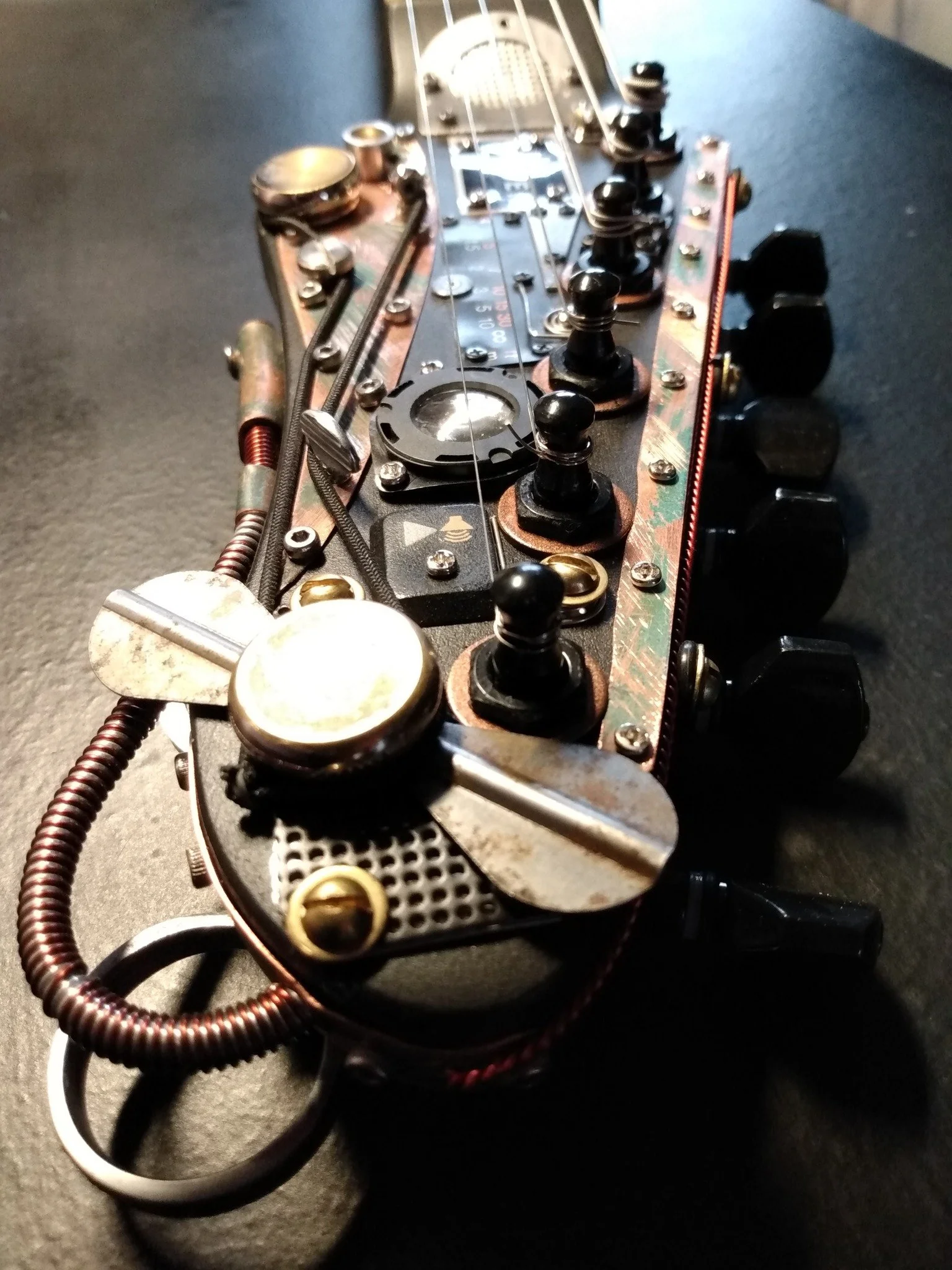 Steampunk Guitar headstock made by Mike Moulton, luthier at Immortal Guitars, featuring various parts from vintage projectors, cameras, lenses, copper tubing, propeller, one of a kind, custom made
