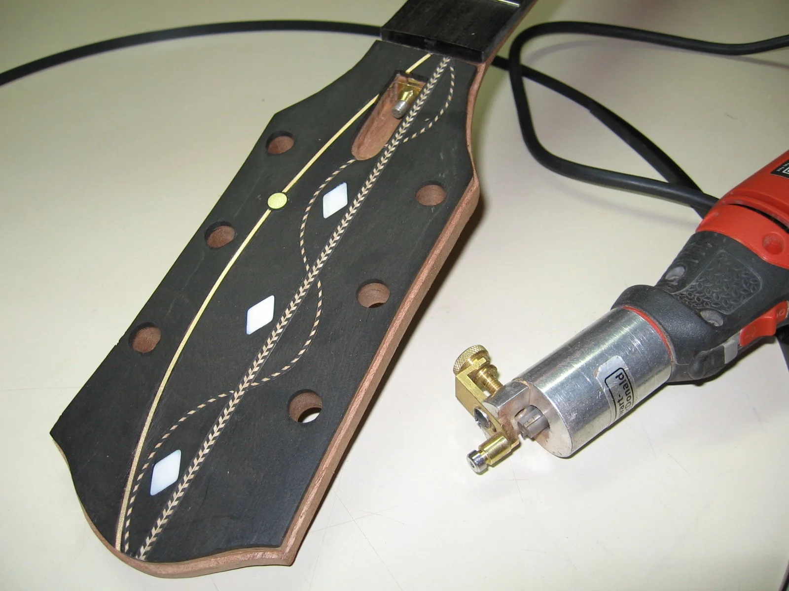 Headstock being custom made by Immortal Guitars using ebony, mother of pearl, gold wire, brass circles, and