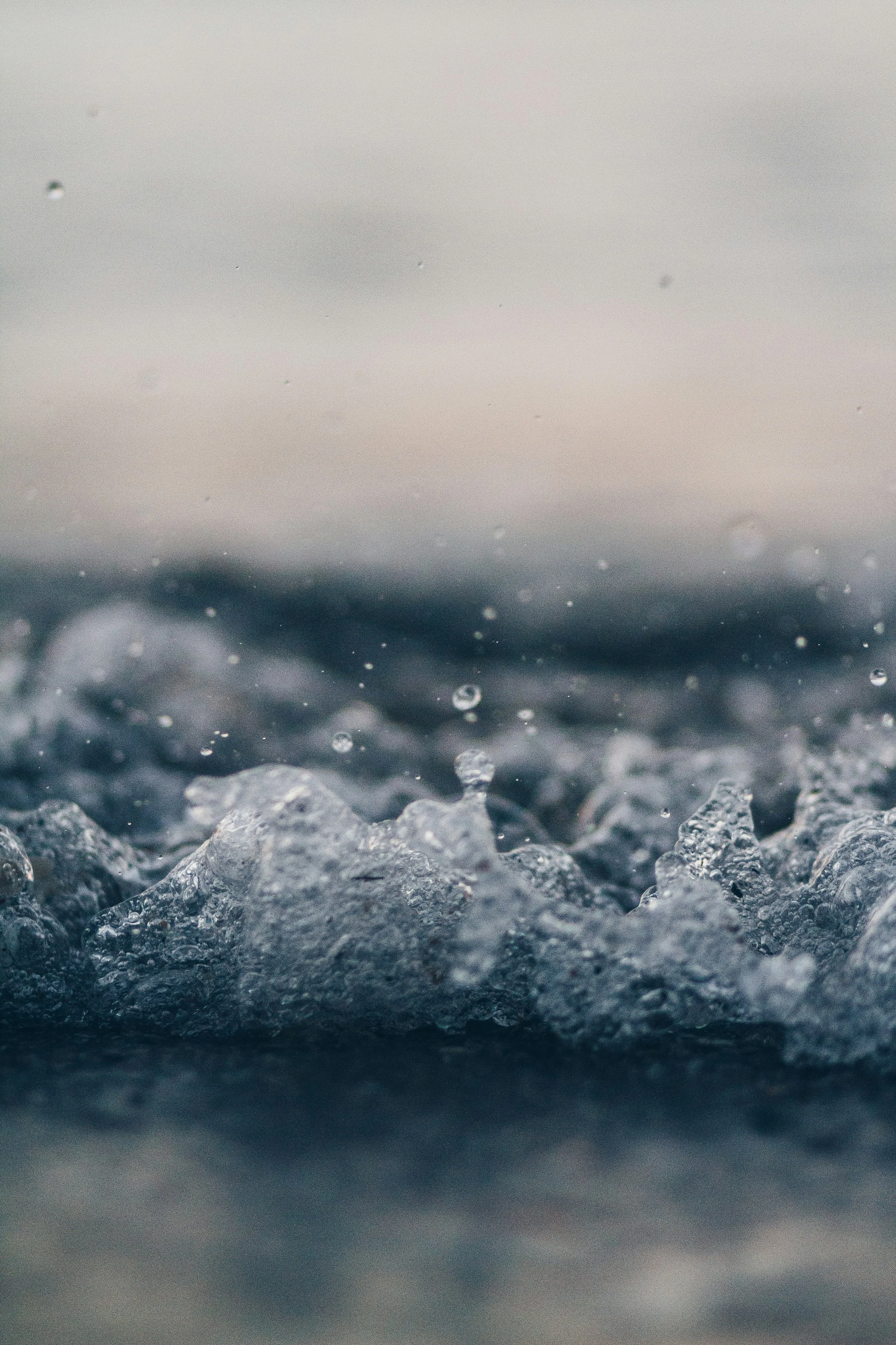Close-up of water droplets on rocks with a misty, cloudy background.