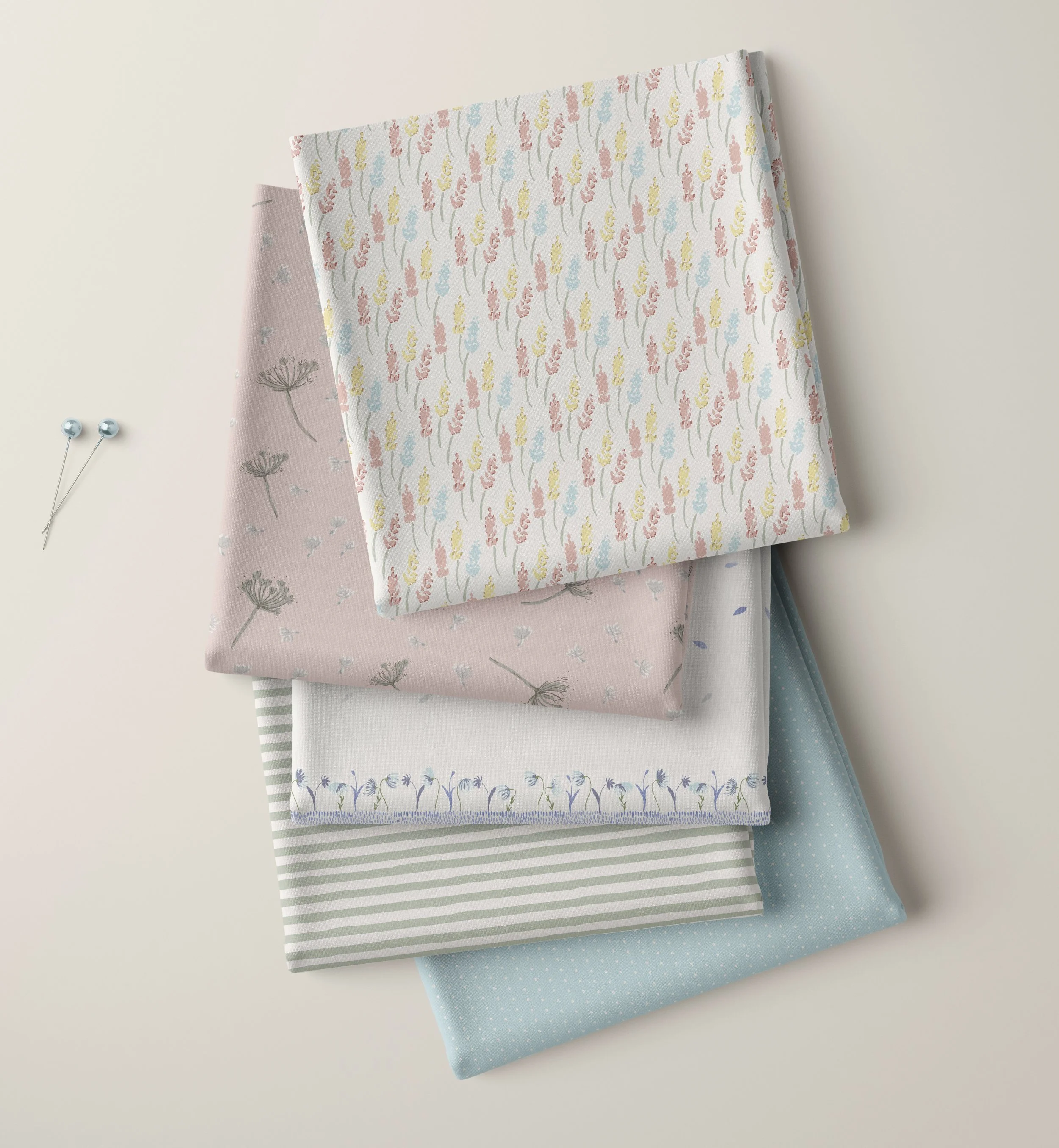 Folded fabric stack featuring pastel floral, dandelion, border, stripe and scattered surface patterns from the Springtime Stories collection.