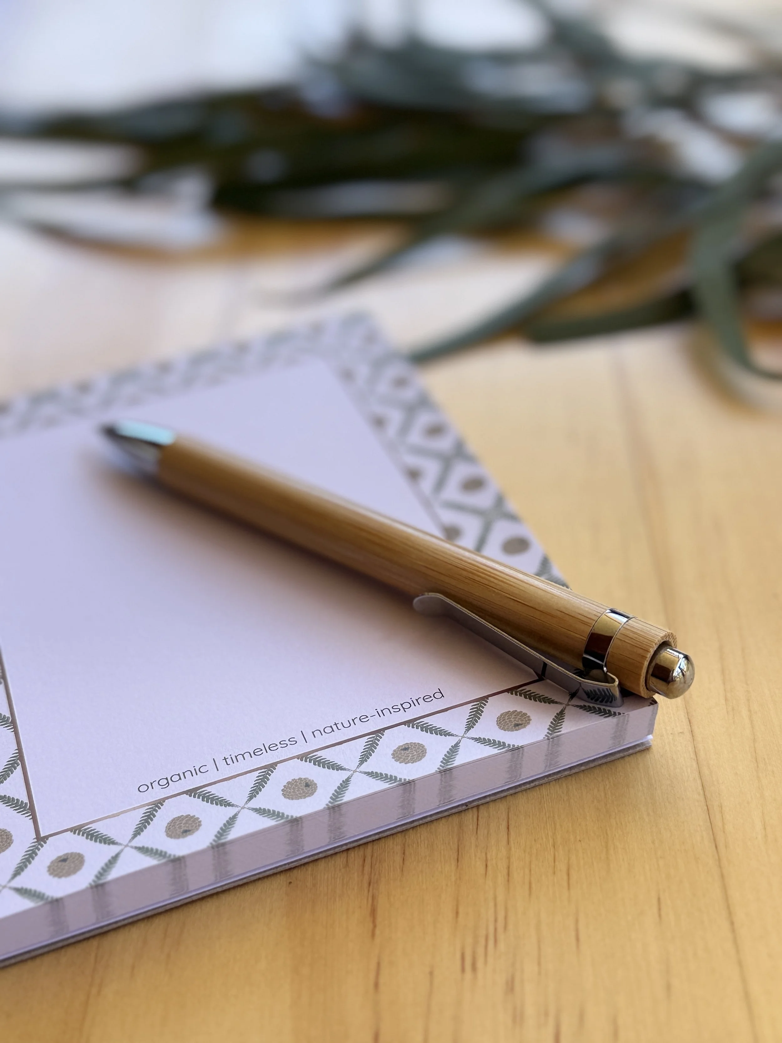 Flourish & Bloom Designs botanical notebook and pen on a timber desk.