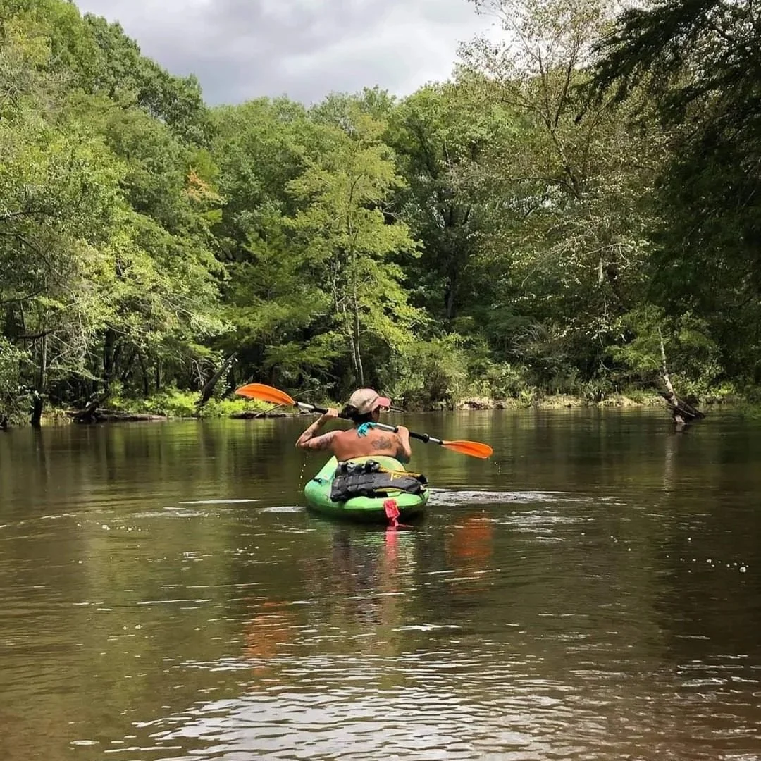 Person kayaking on the Ohoopee River surrounded by trees at Ohoopee River RV & Camp Resort