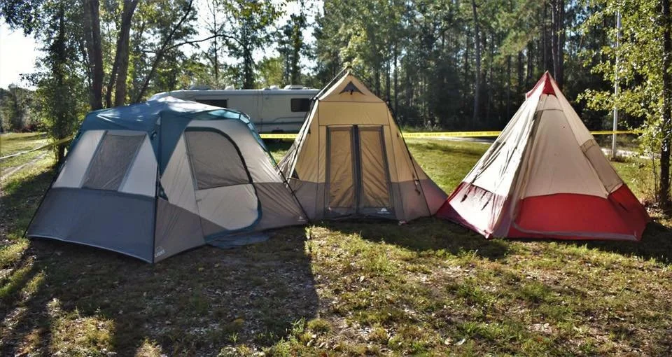 Tents pitched among the trees at a wooded campsite at Ohoopee River RV & Camp Resort