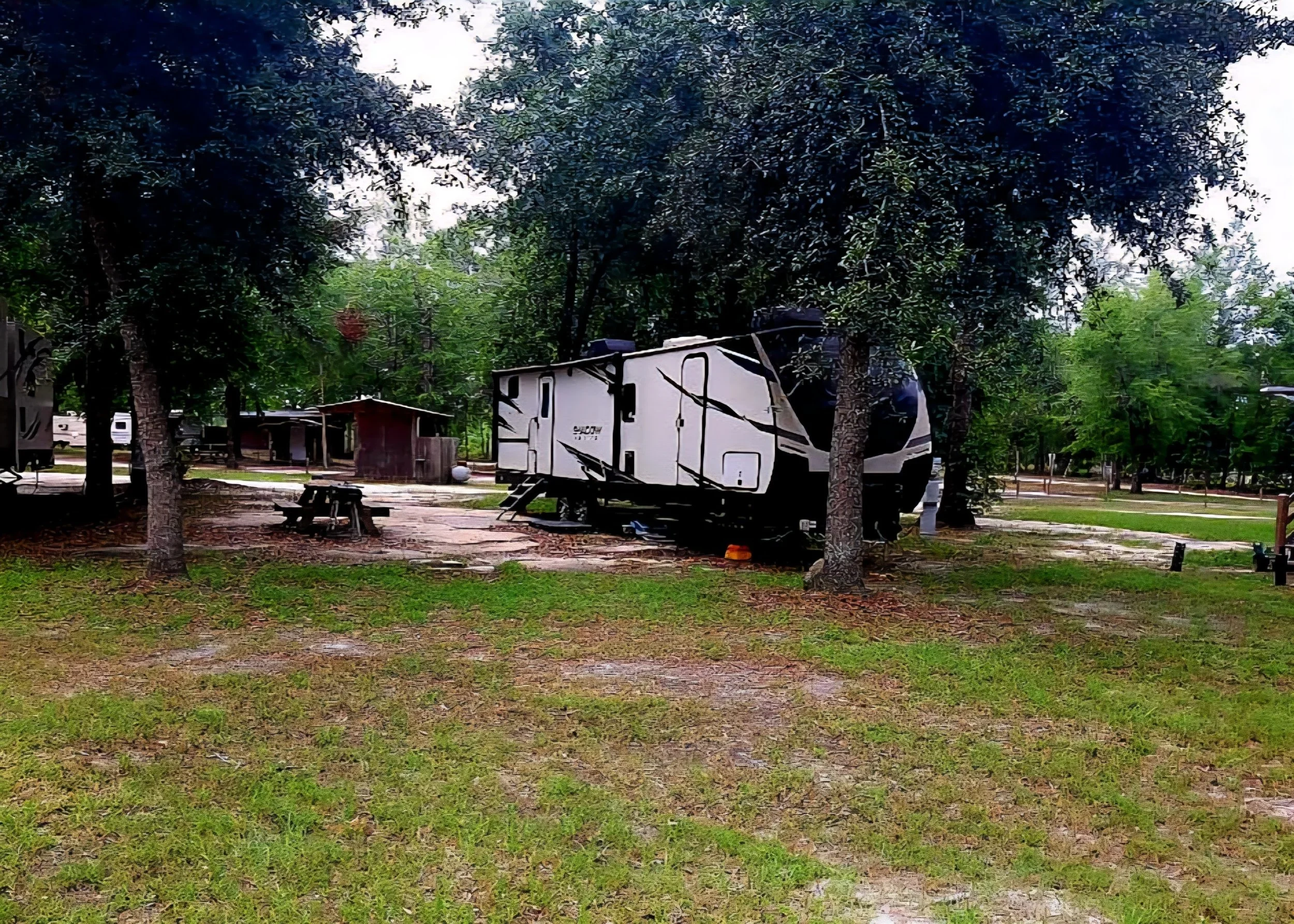 RV parked at a shaded, full-hookup campsite among trees at Ohoopee River RV & Camp Resort
