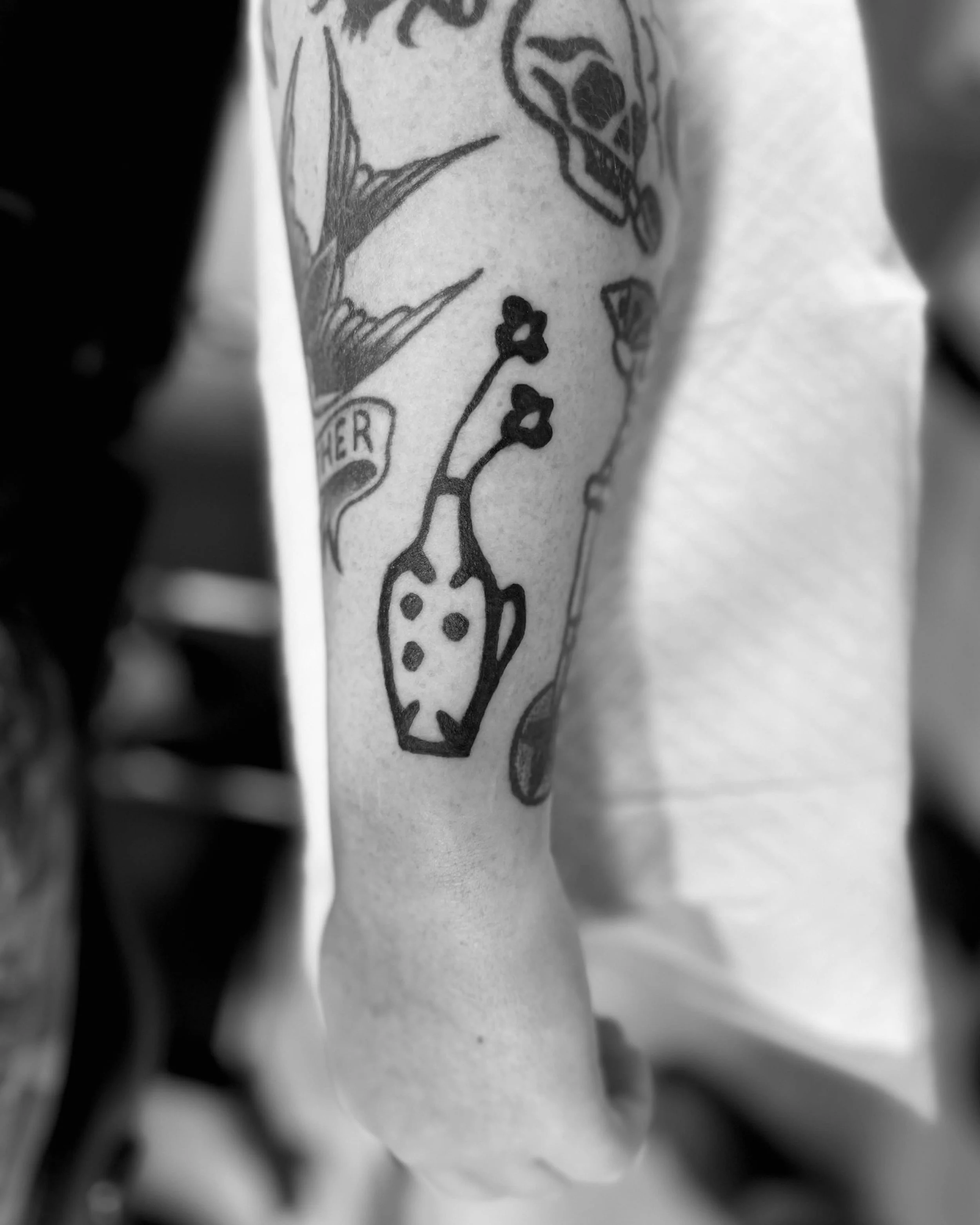 Small vase lino-print inspired tattoo on the forearm by Pip 