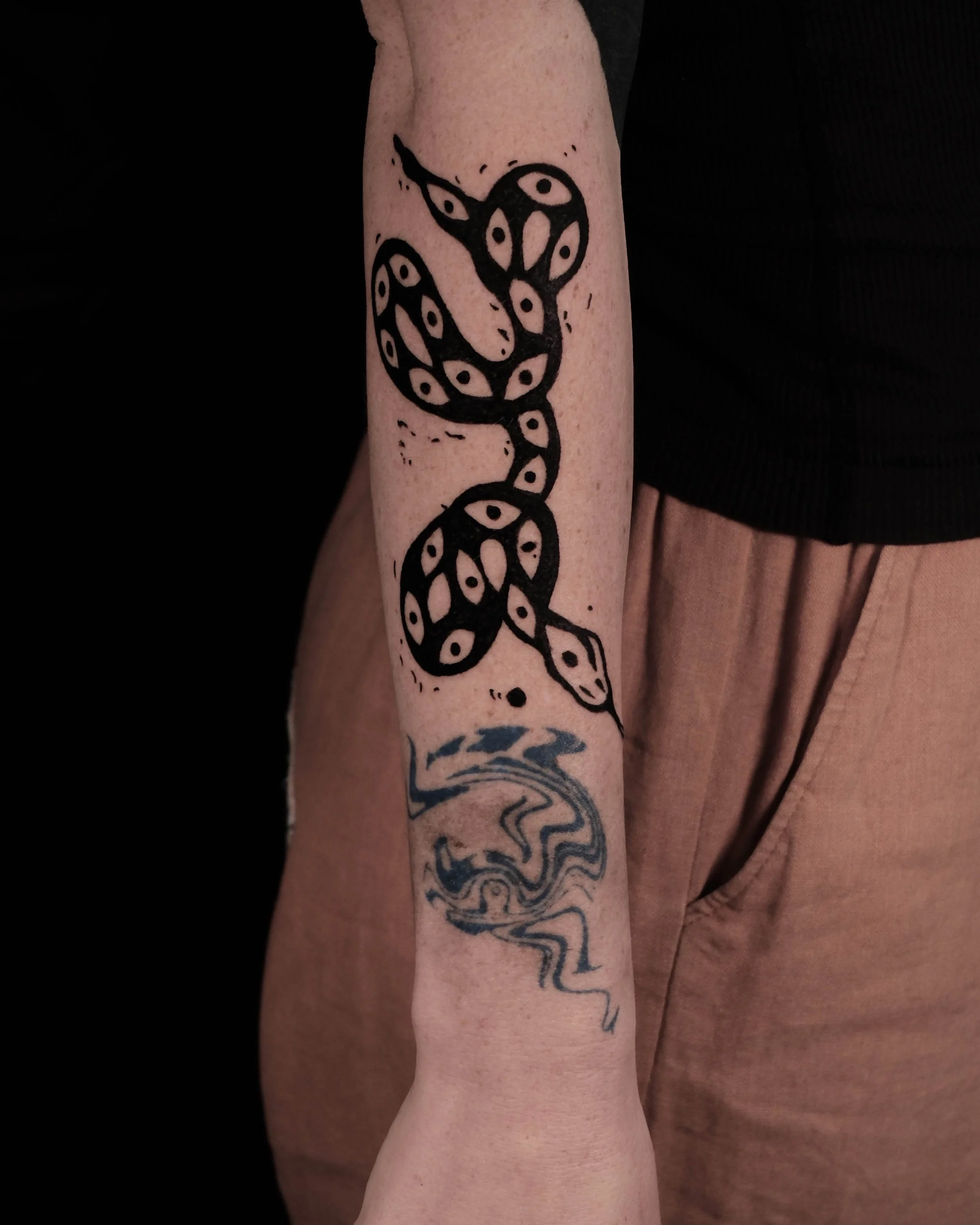 Lino-print bold snake tattooed wrapped on a person's arm by Pip