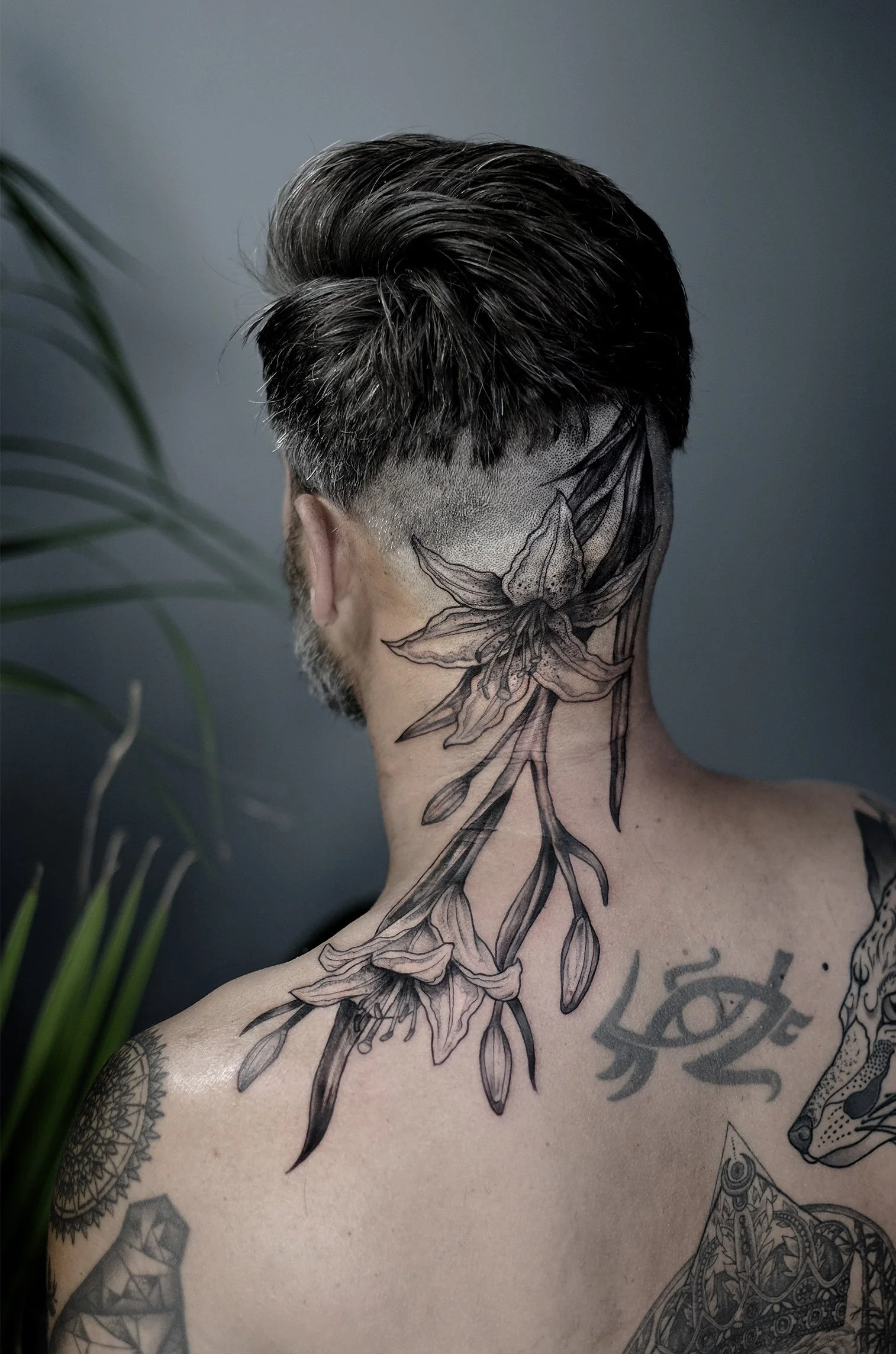 Bold blackwork lily tattoo on neck and head tattooed by Jak Rapmund