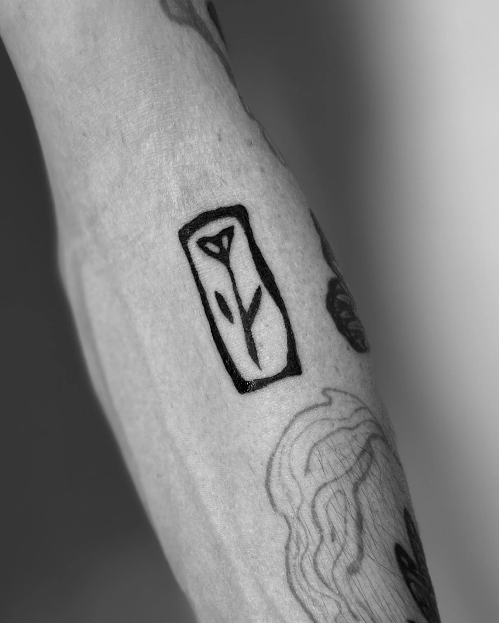 Small floral lino-print inspired tattoo on the forearm by Pip 