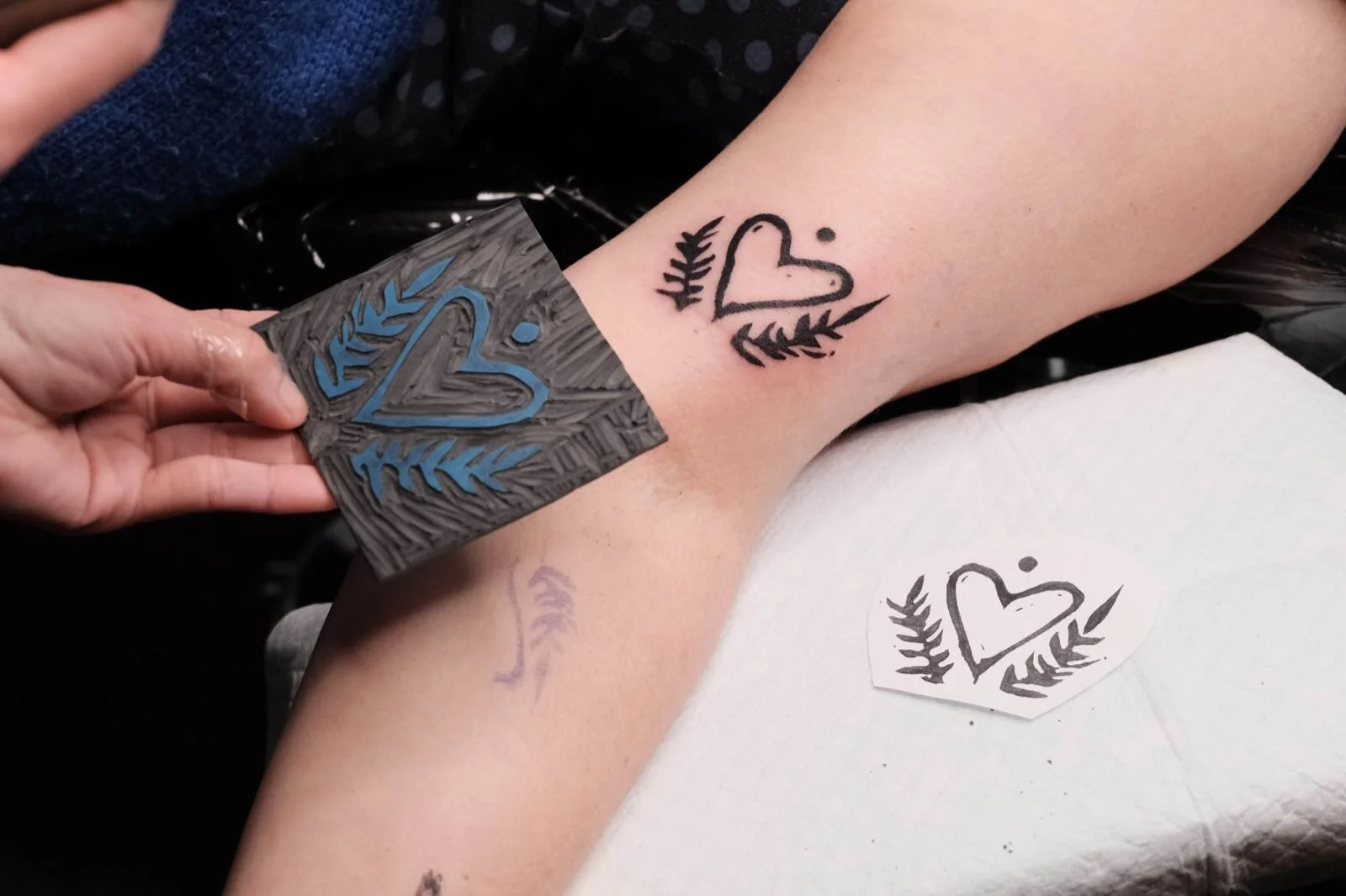 A lino-print heart design tattooed on the inner arm by Pip