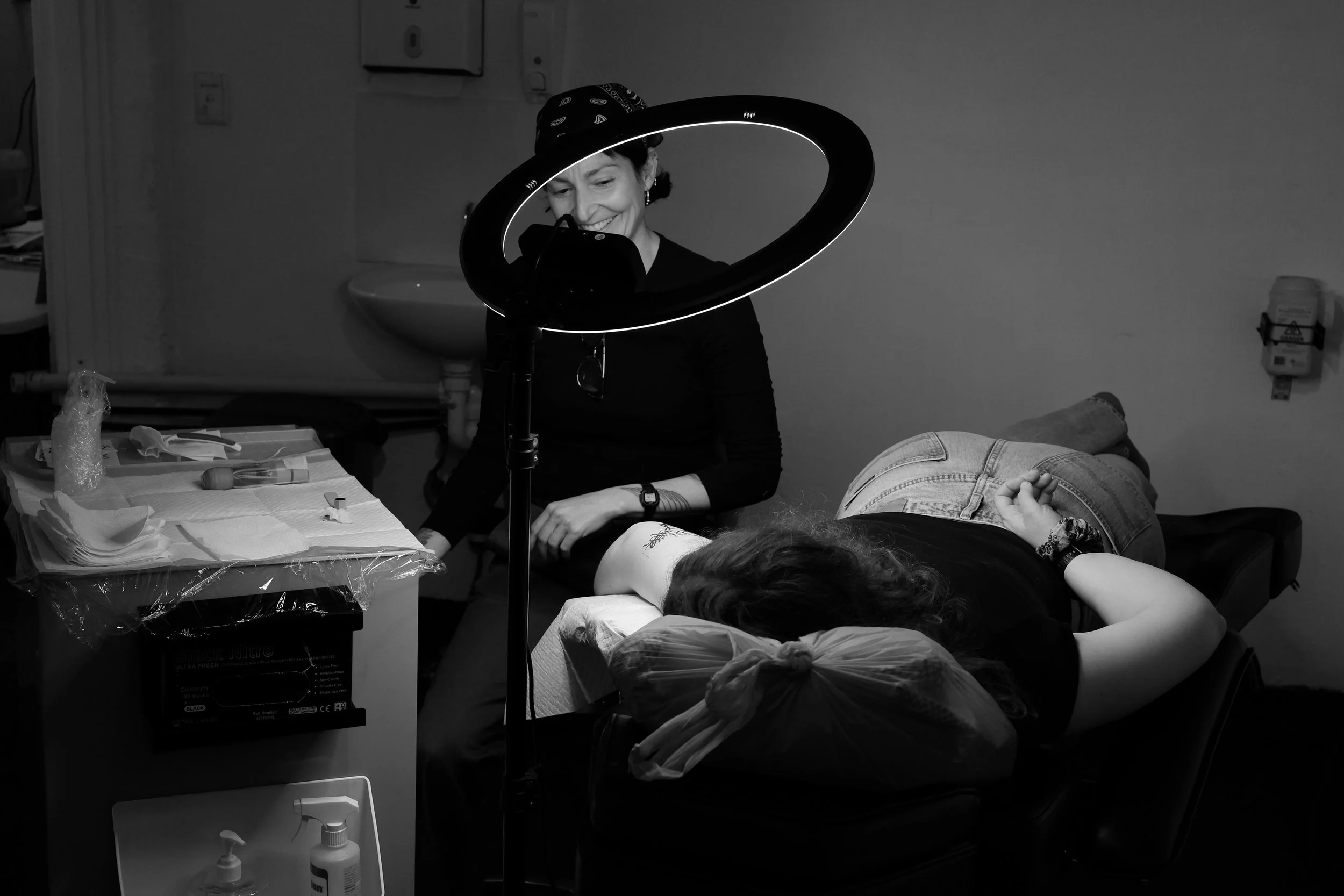 Pip smiling and talking to her client while tattooing in Together Tattoo studio