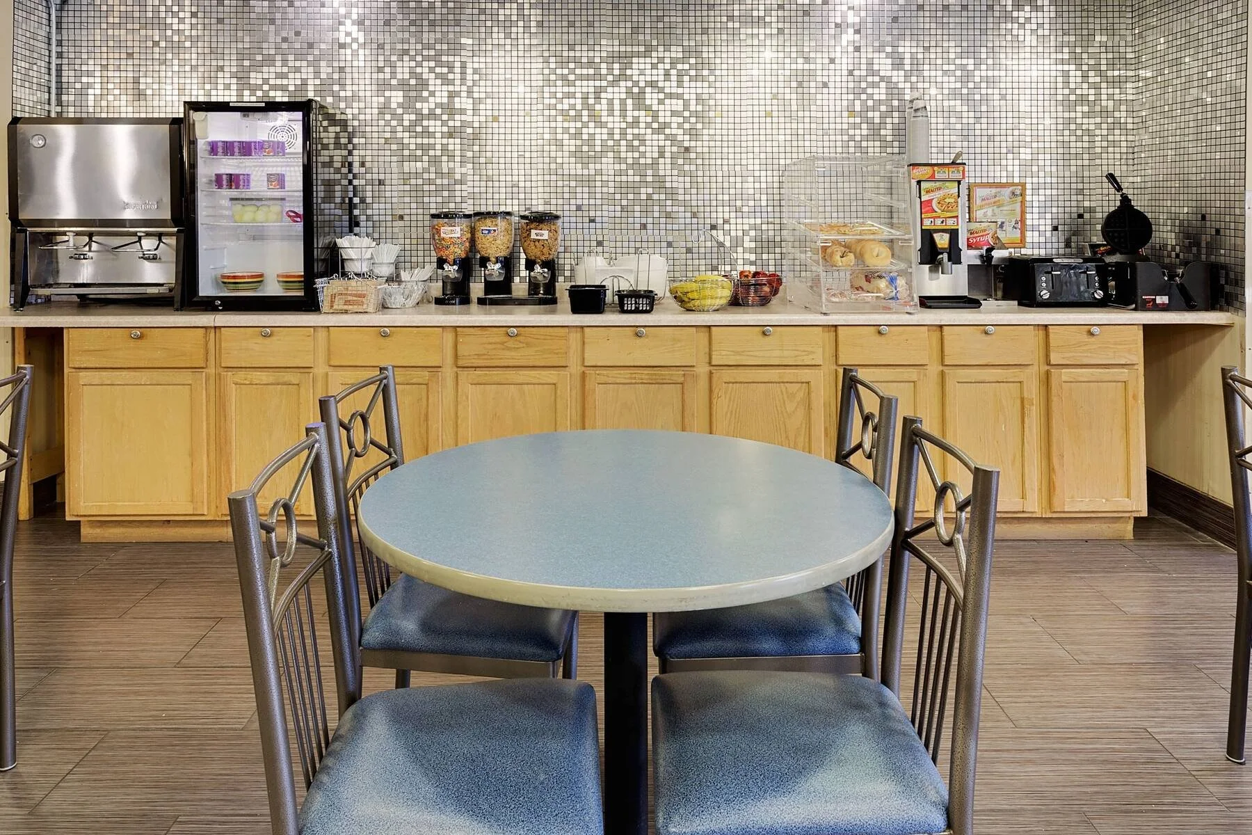 Breakfast buffet counter with cereal dispensers, toaster, and coffee machine in a cafeteria setting.