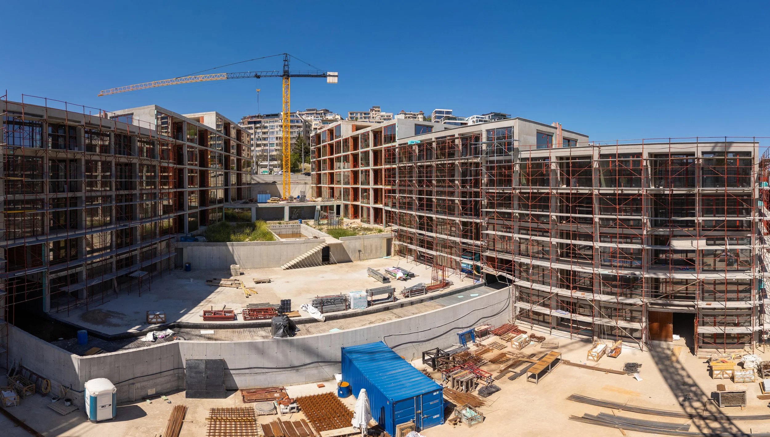 panoramic-view-modern-residential-construction-site-with-scaffolding-cranes-unfinished-buildings-clear-blue-sky-urban-environment.jpg