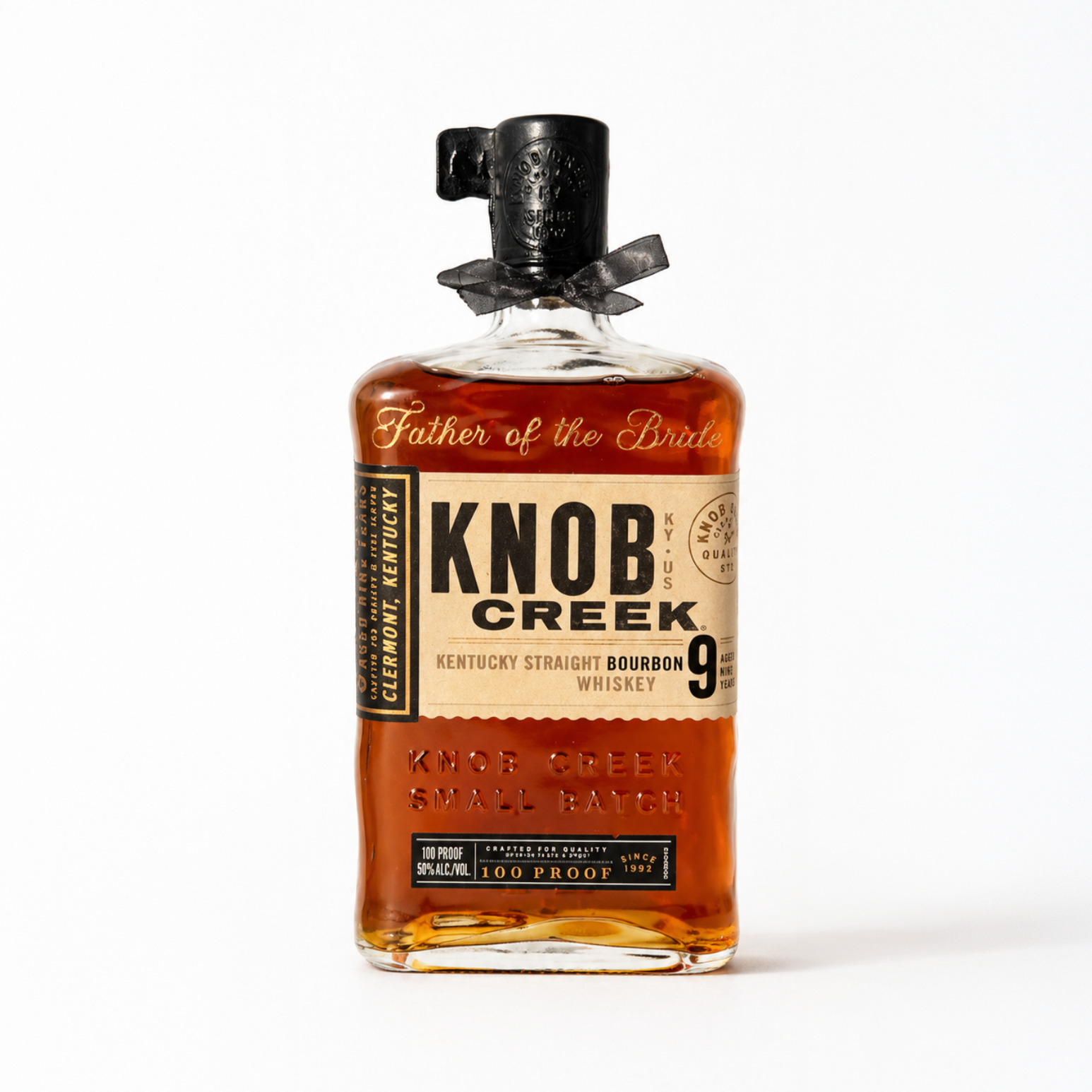 A bottle of Knob Creek Kentucky Straight Bourbon Whiskey with a black cap and a black ribbon around it, labeled 'Father of the Bride'.