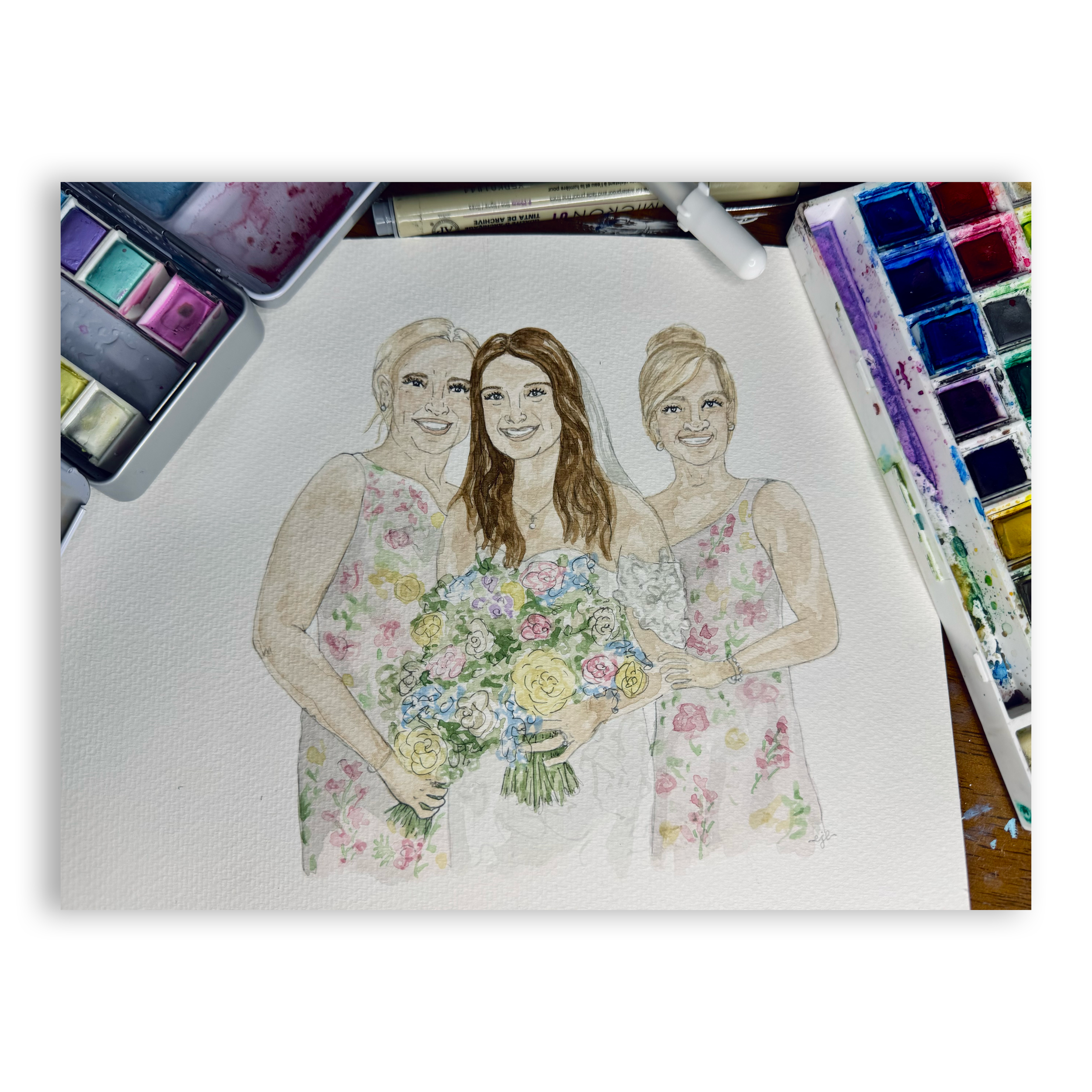A watercolor painting of three women smiling, with a floral bouquet at the bottom, surrounded by watercolor paints and art supplies.