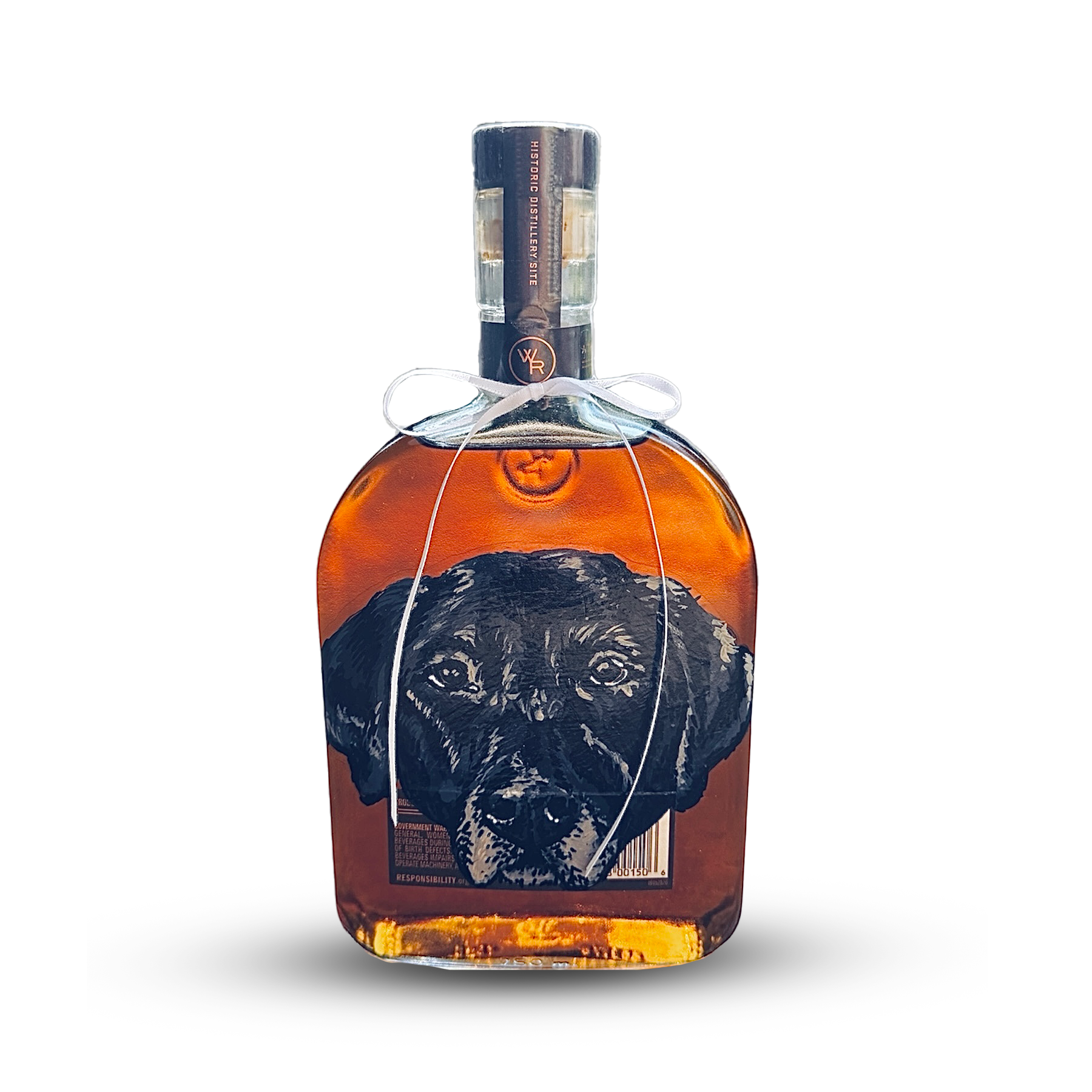 A bottle of whiskey with a black Labrador retriever puppy on the label. The bottle is wrapped in a white ribbon.