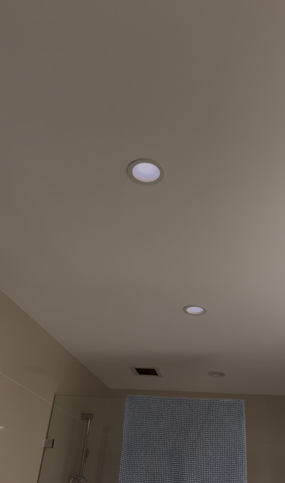 Ceiling with recessed lighting fixtures in a room with a towel hanging on a towel rack