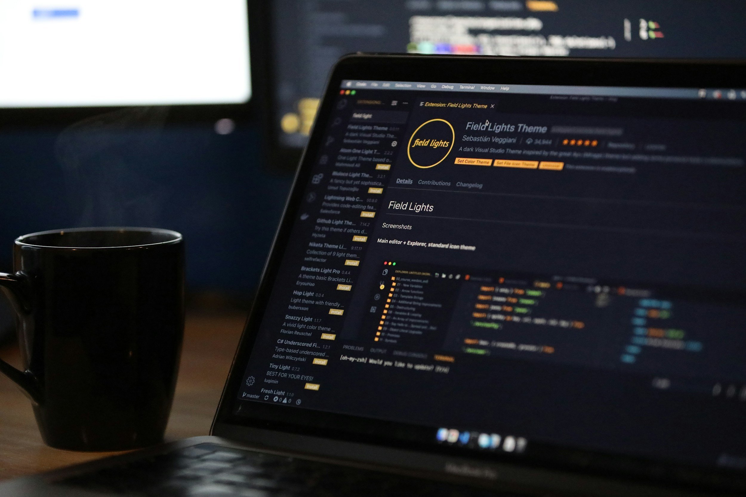 A laptop screen displaying a dark theme coding interface, with a coffee mug on the desk beside it.