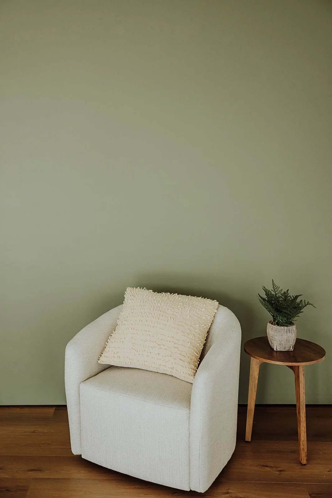 Cream boucle chair and side table against a sage wall at The ANS Collective photo studio