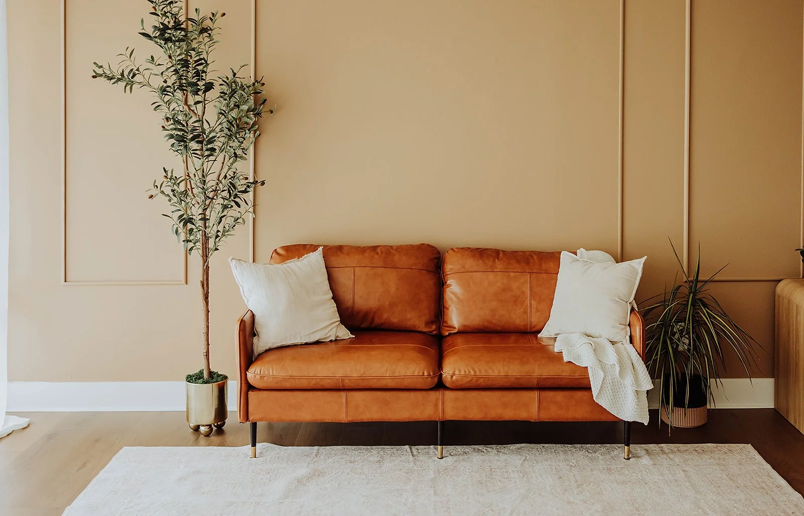 Leather sofa with throw pillows beside tall windows at The ANS Collective photo studio in Grandville, MI