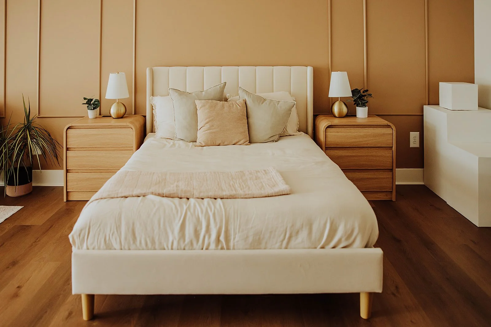 Cream upholstered bed with warm wood nightstands in The Suite set at The ANS Collective photo studio, Grandville MI