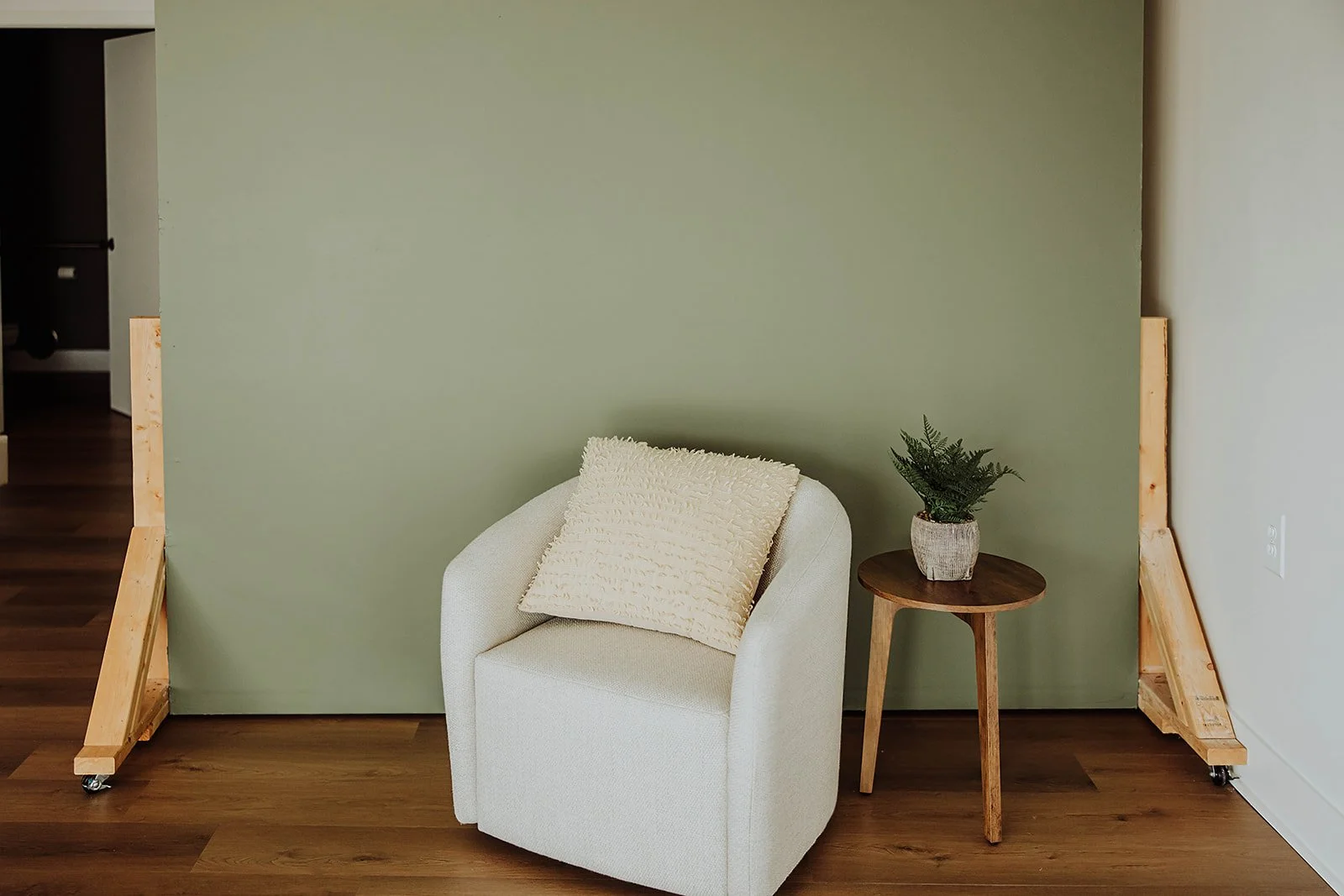 White boucle accent chair against the sage wall at The ANS Collective photo studio, Grandville MI