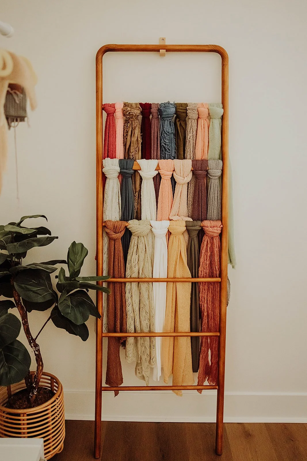 Wooden ladder rack of newborn wraps and fabrics in neutral tones at The ANS Collective photo studio