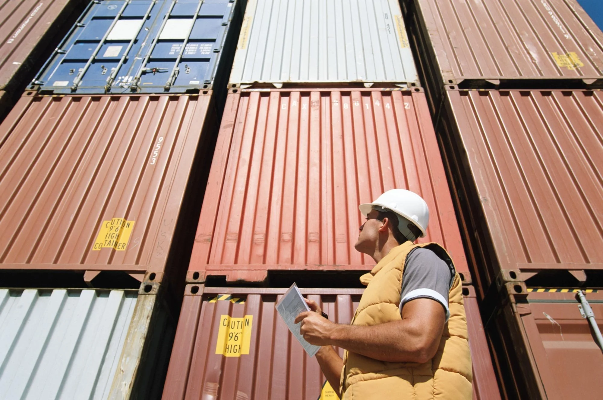man in hard hat inspecting shipping containers