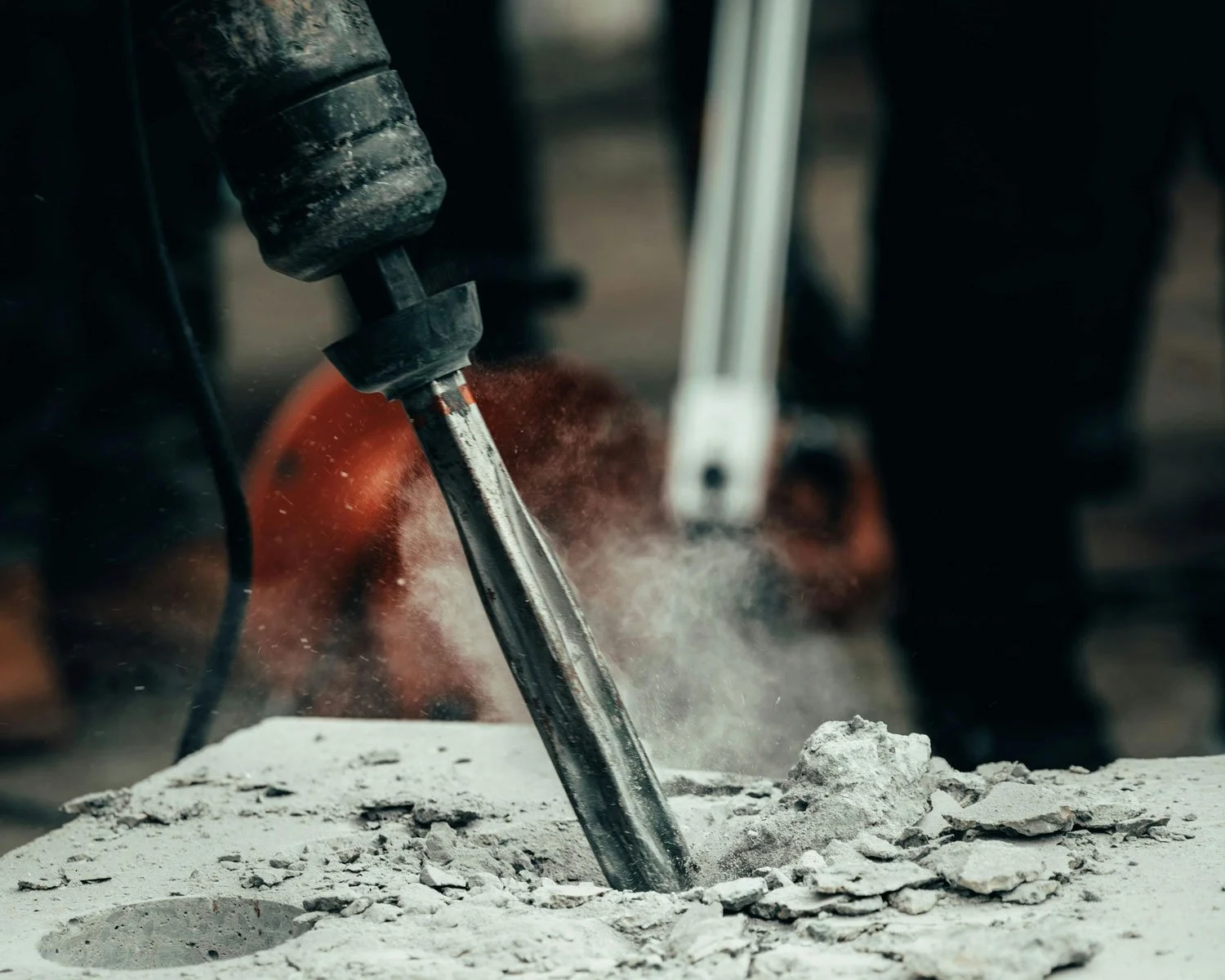 close up of power tool breaking up concrete slab during vibration risk assessment