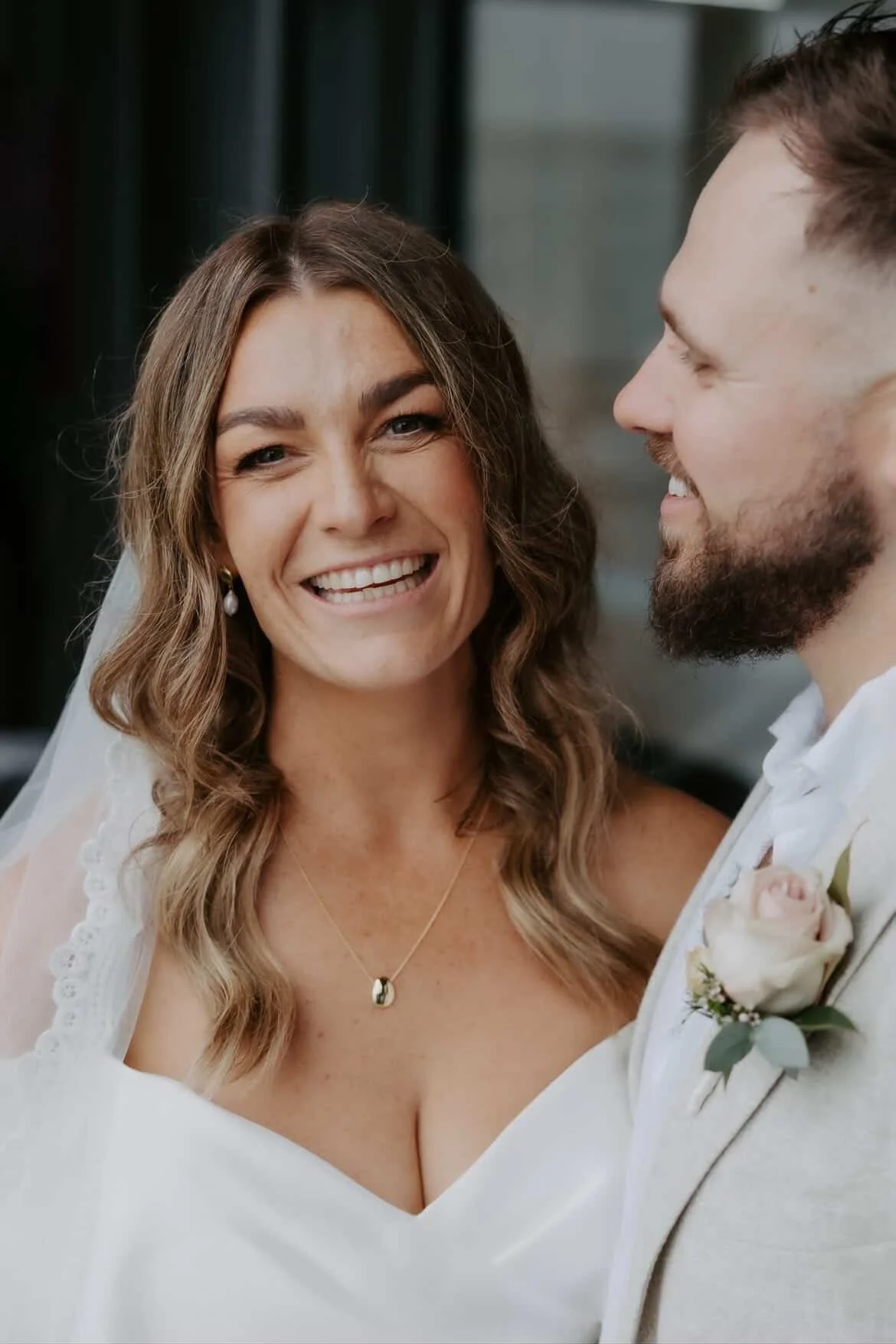 A smiling woman in a wedding dress standing next to a man in a suit, both at a wedding ceremony.