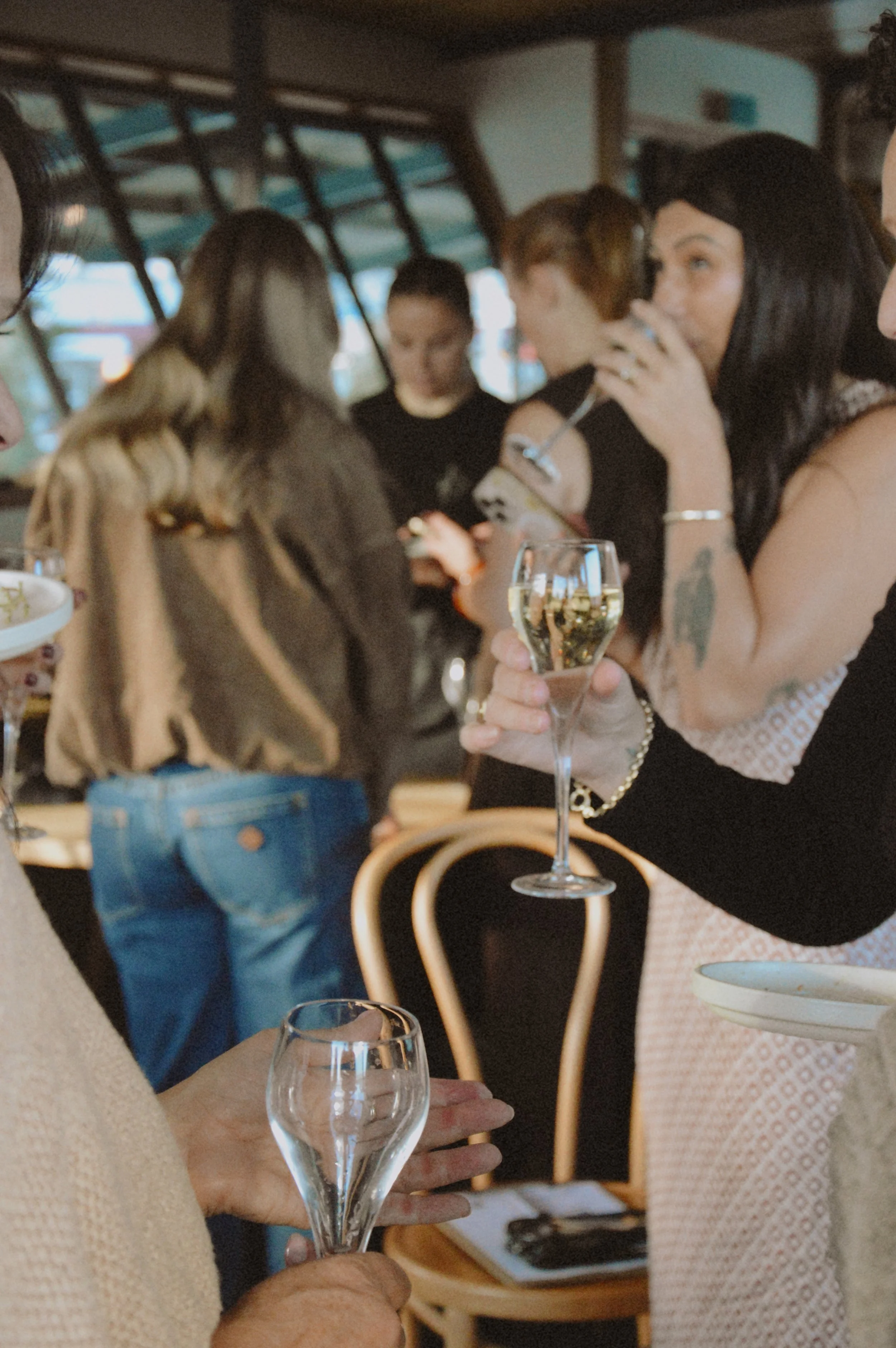 People gathered around a table at a social event, holding glasses of wine and engaging in conversation.