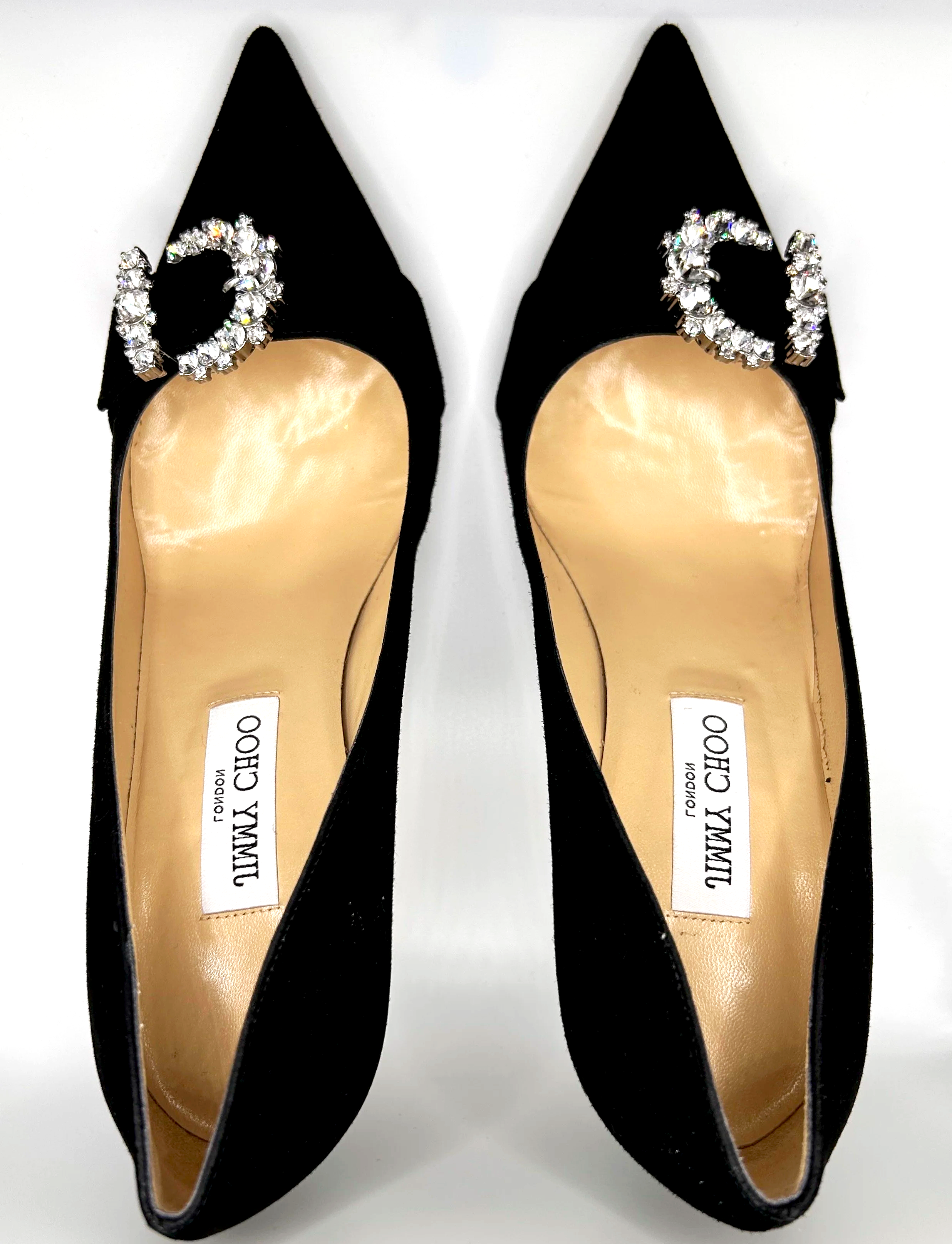 Black high-heeled shoes with pointed toes, decorated with jeweled initials 'C' on the front. The shoes are labeled 'Jimmy Choo' on the insole.