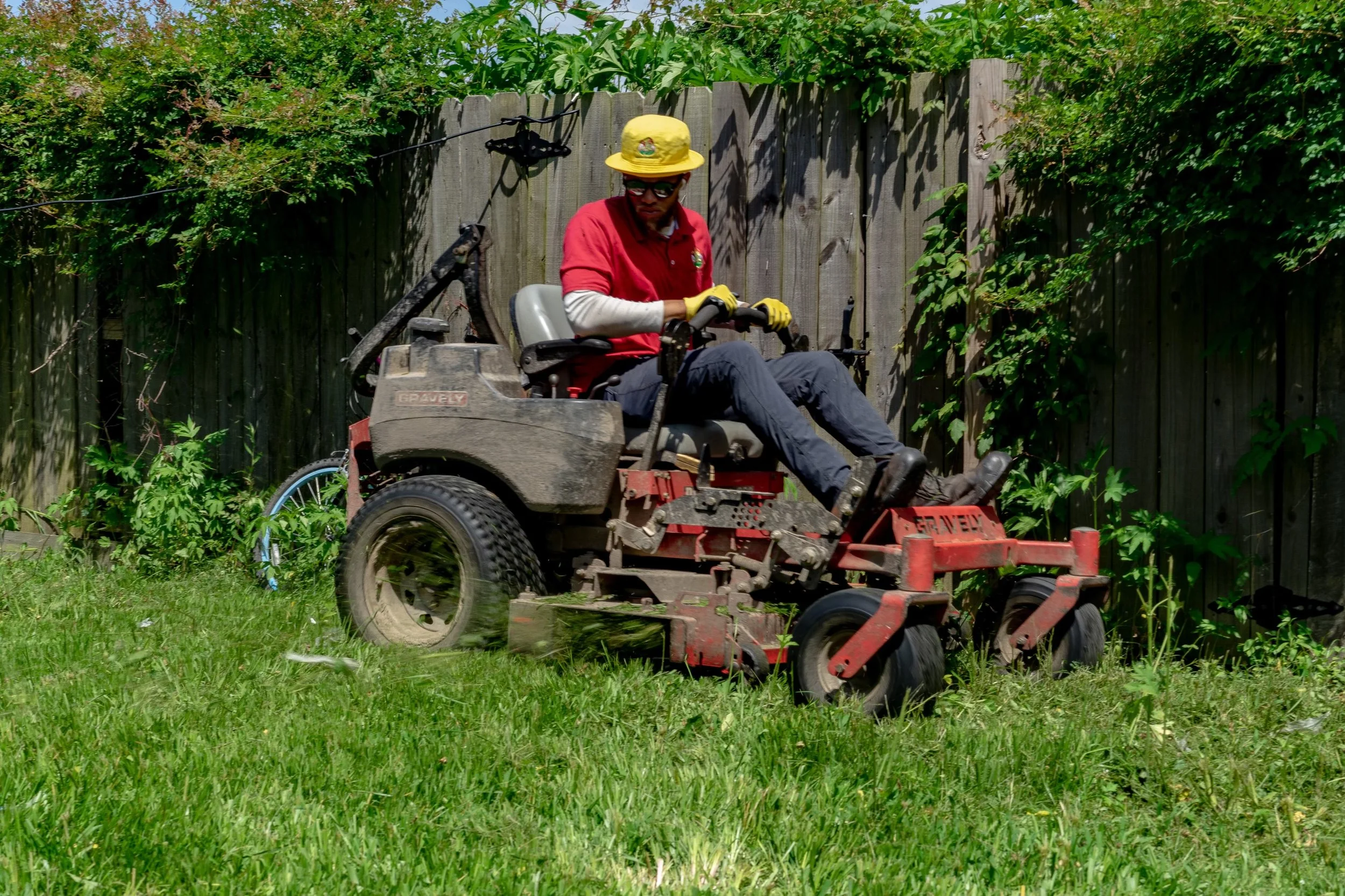 Overgrown property cleanup is being taking care of by a J&B Lawn & Landscaping professional using a commercial mower.