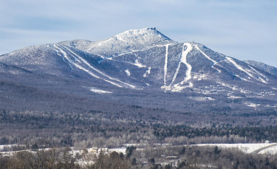 Snow-covered mountain with ski trails visible on the slopes and a small ski slope at the top.
