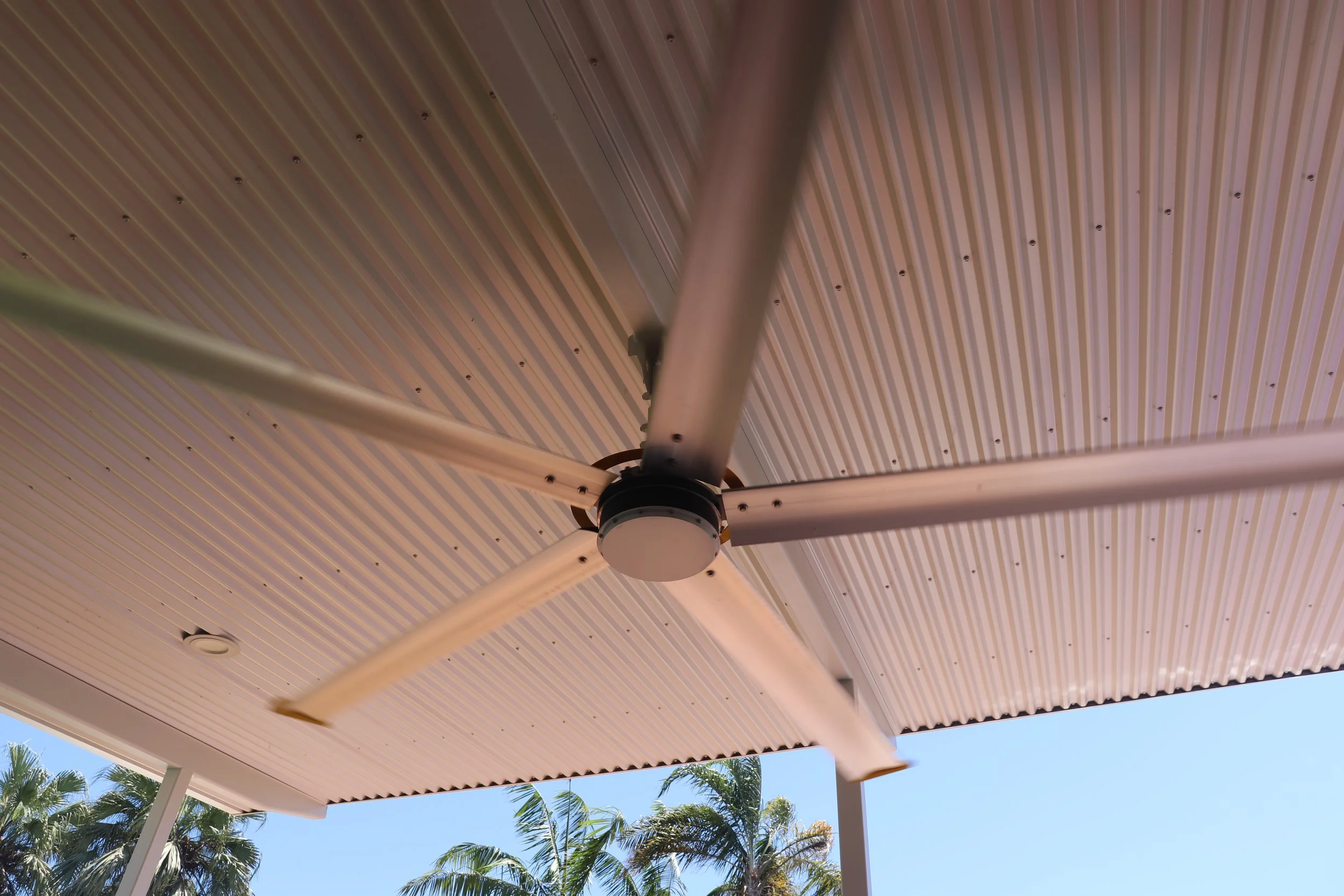 Small residential HVLS fan. Part of an Darwin outdoor area with palm trees and a clear blue sky in the background. Darwin. Top End