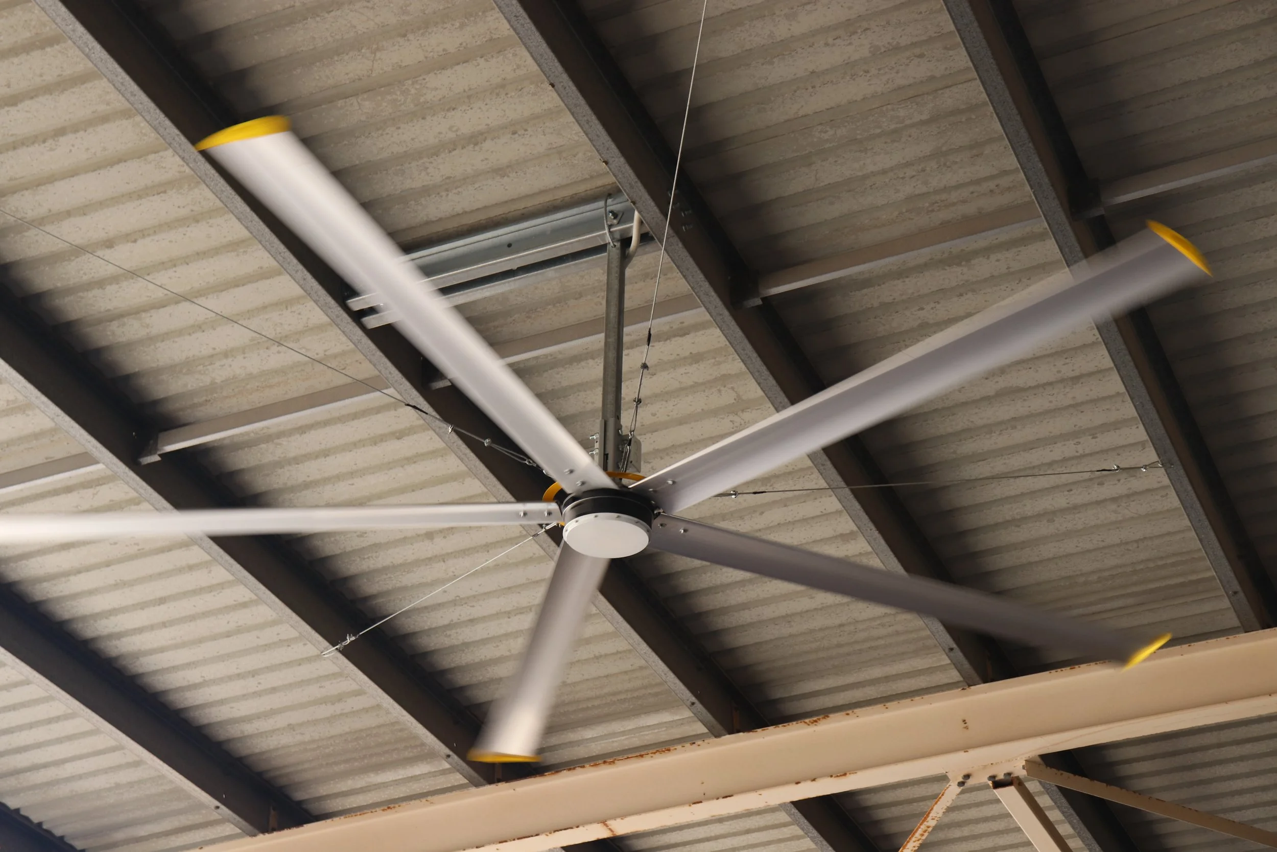 Warehouse shed with a big yellow HVLS fan cooling the area