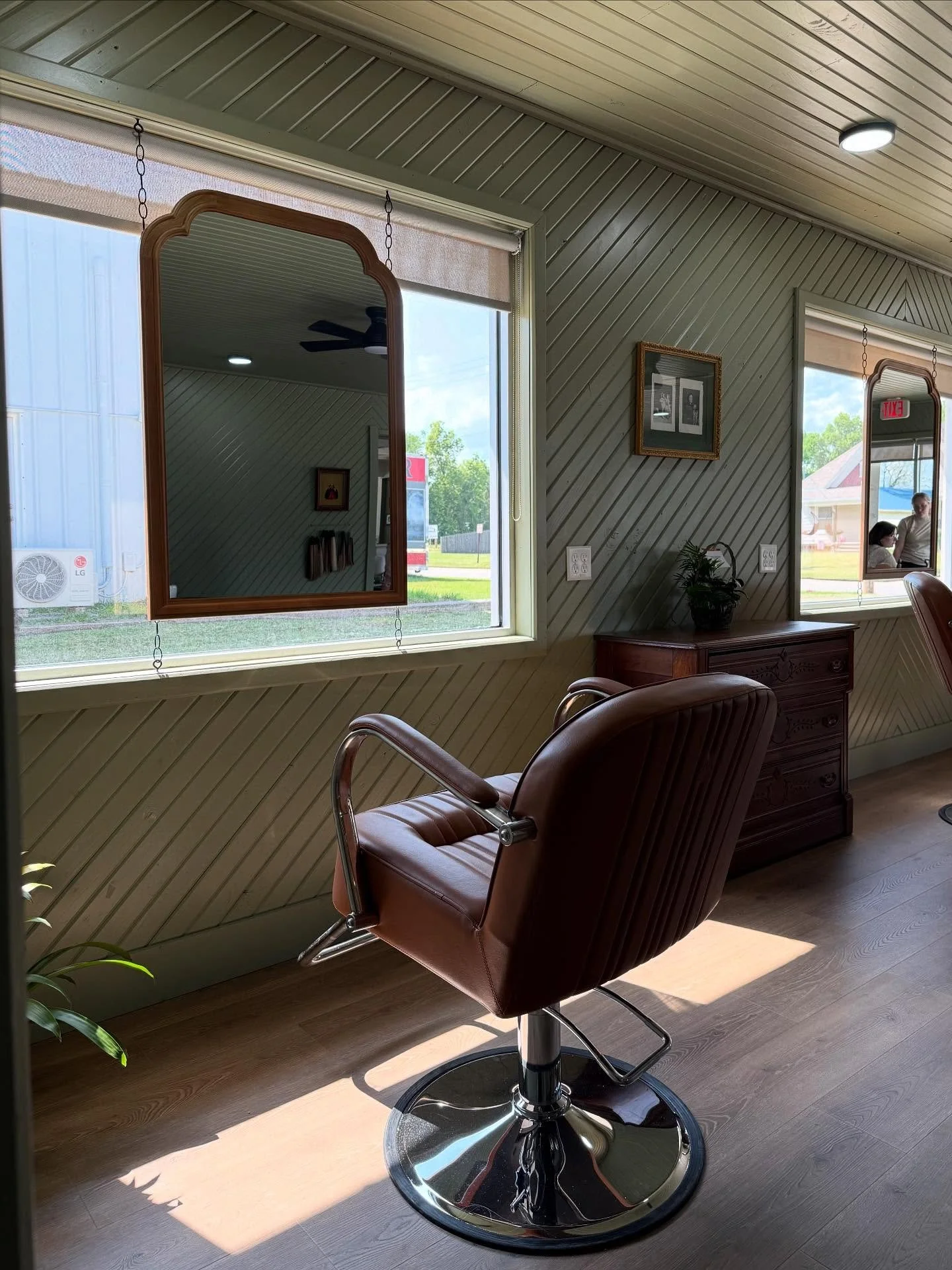 An image of a salon chair facing a window and mirror.
