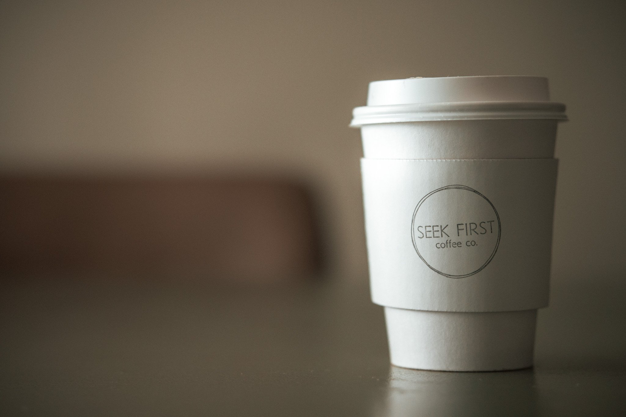 An image of a cup with a Seek First Coffee Co. Cup holder.