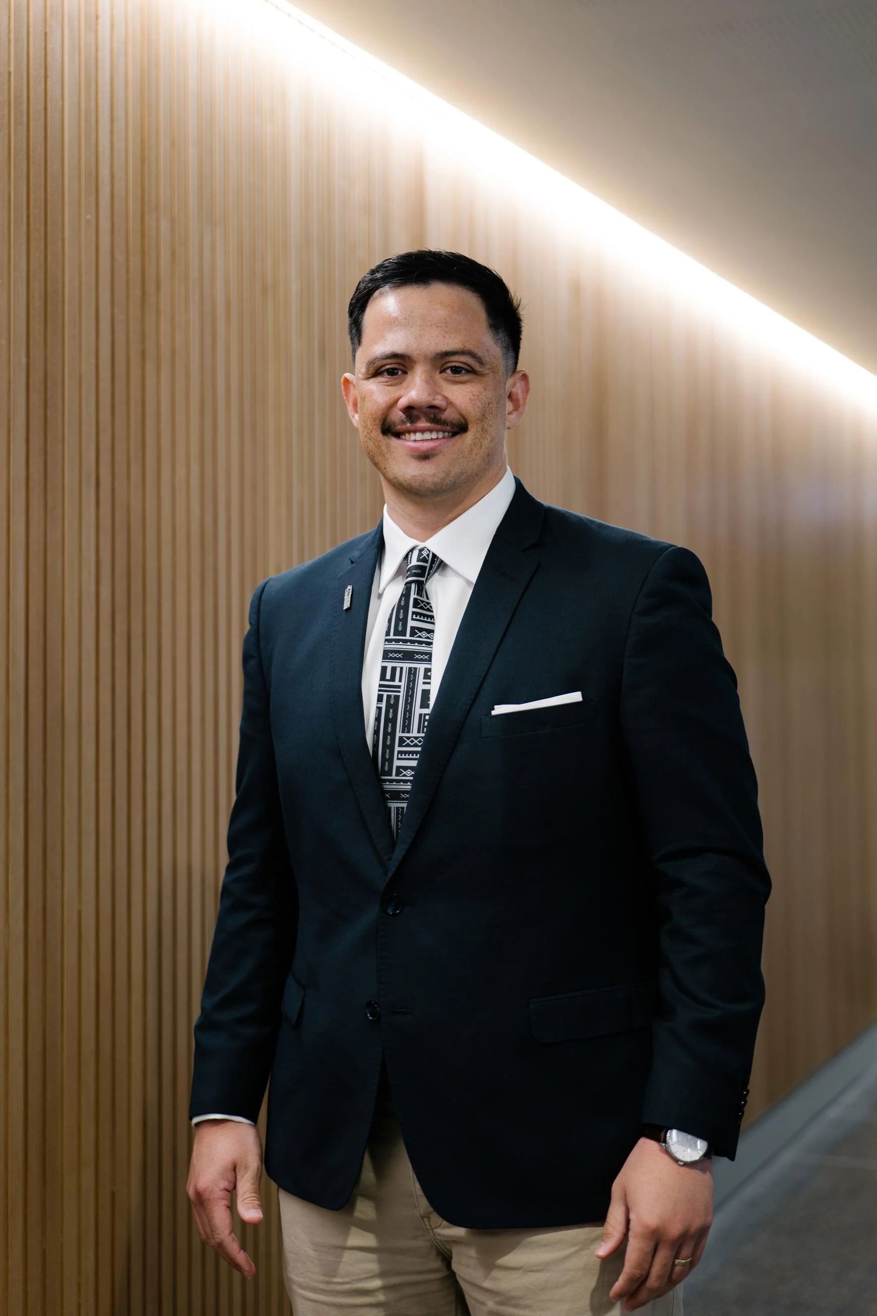 Photo of Dr Sese wearing a suit and tie looking at the camera smiling.