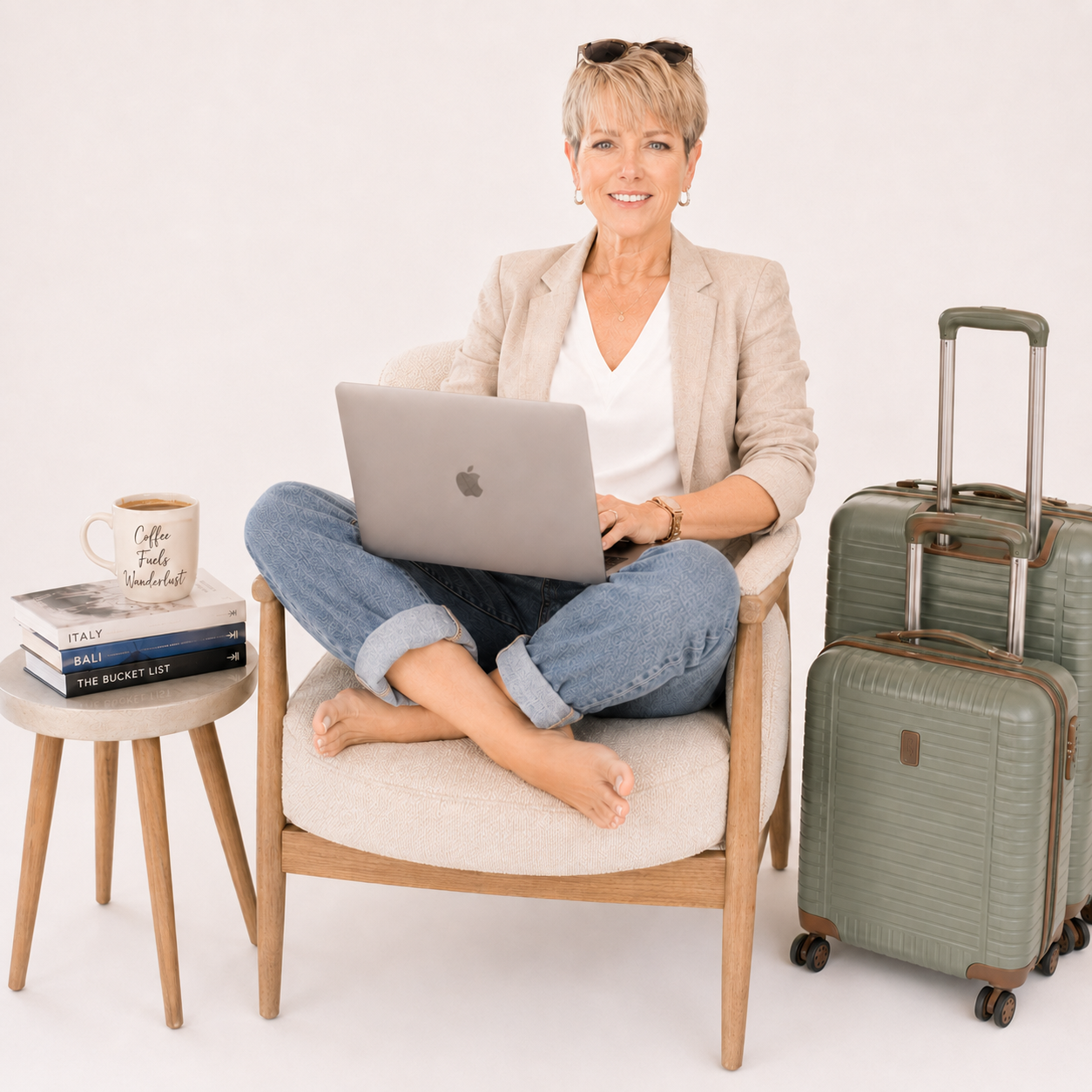 Elisabeth of Willow & Wander Travel sitting in a Nordic style chair, smiling, with her MacBook typing her latest travel ideas and helpful tips to ensure her clients have the most tailored travel experience.