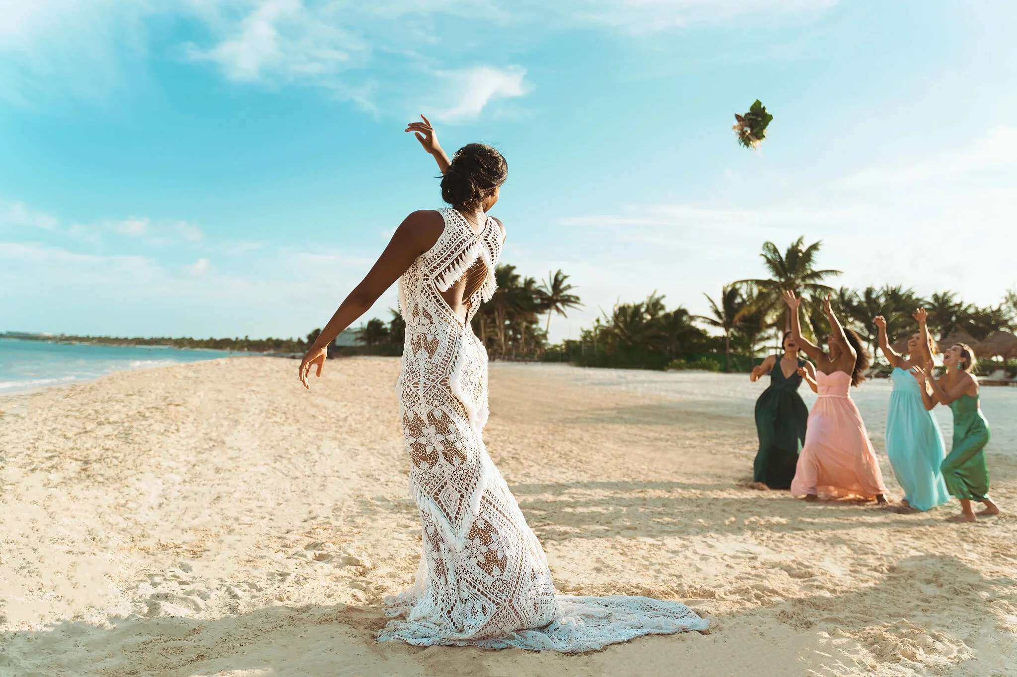 A bride throwing her bouquet during a luxury beach destination wedding ceremony; an intentional romantic celebration curated by Willow & Wander Travel.