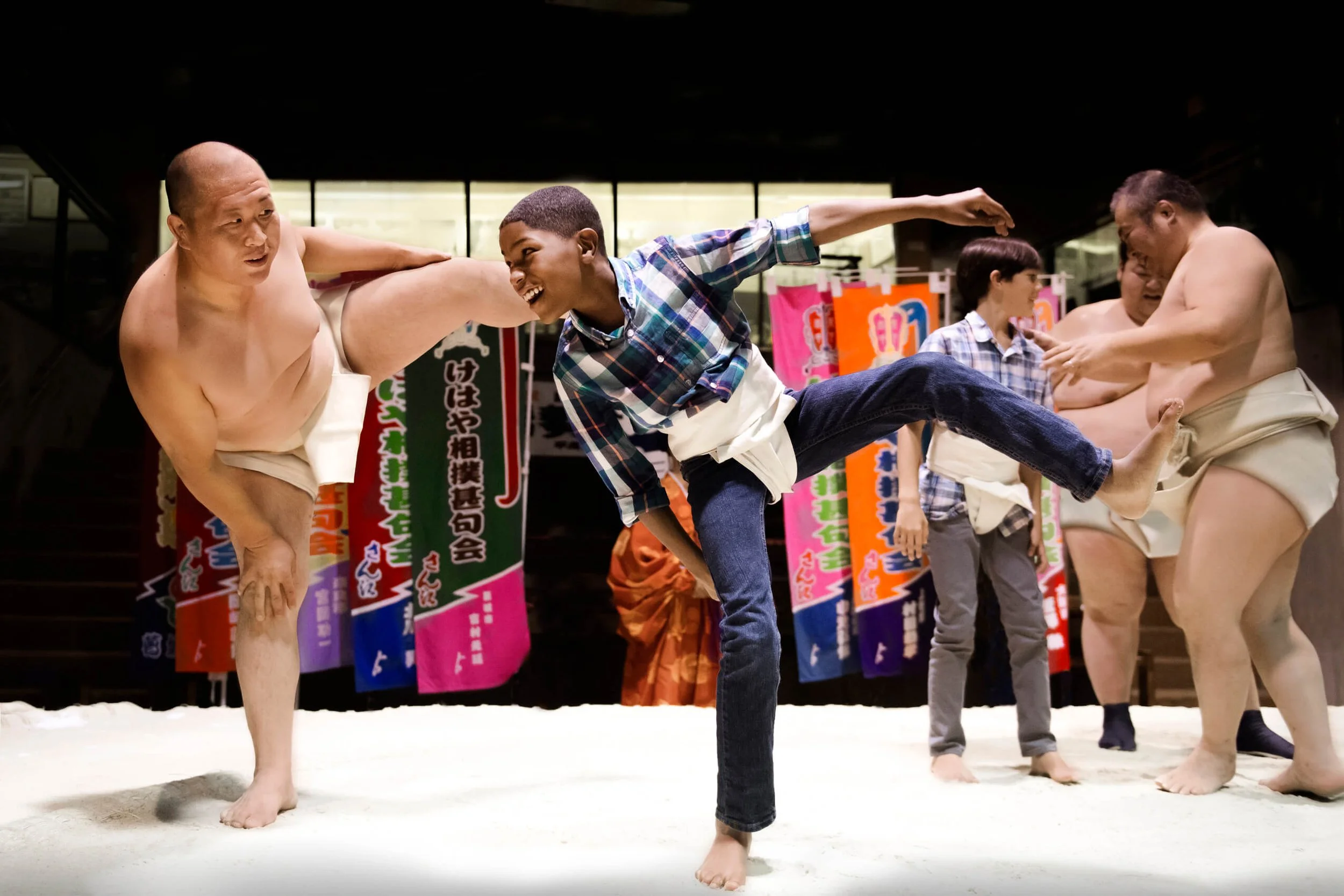 A young boy practicing traditional moves in a sumo ring with professional wrestlers in Japan; an intentional family cultural discovery curated by Willow & Wander Travel.