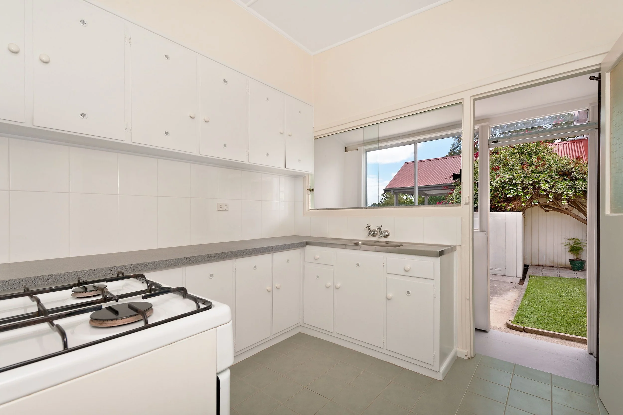 freshly painted, repaint of white kitchen with cabinets, a small sink, a stove, and a large window