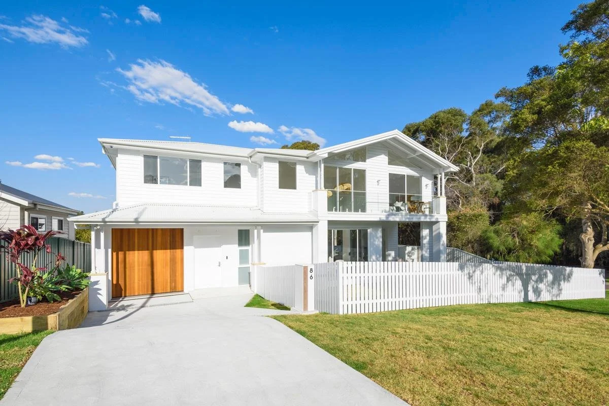 Modern two-story white house with wooden garage door, large glass windows and a small front yard, Painting the exterior of home in Sutherland Shire, Sydney, NSW.