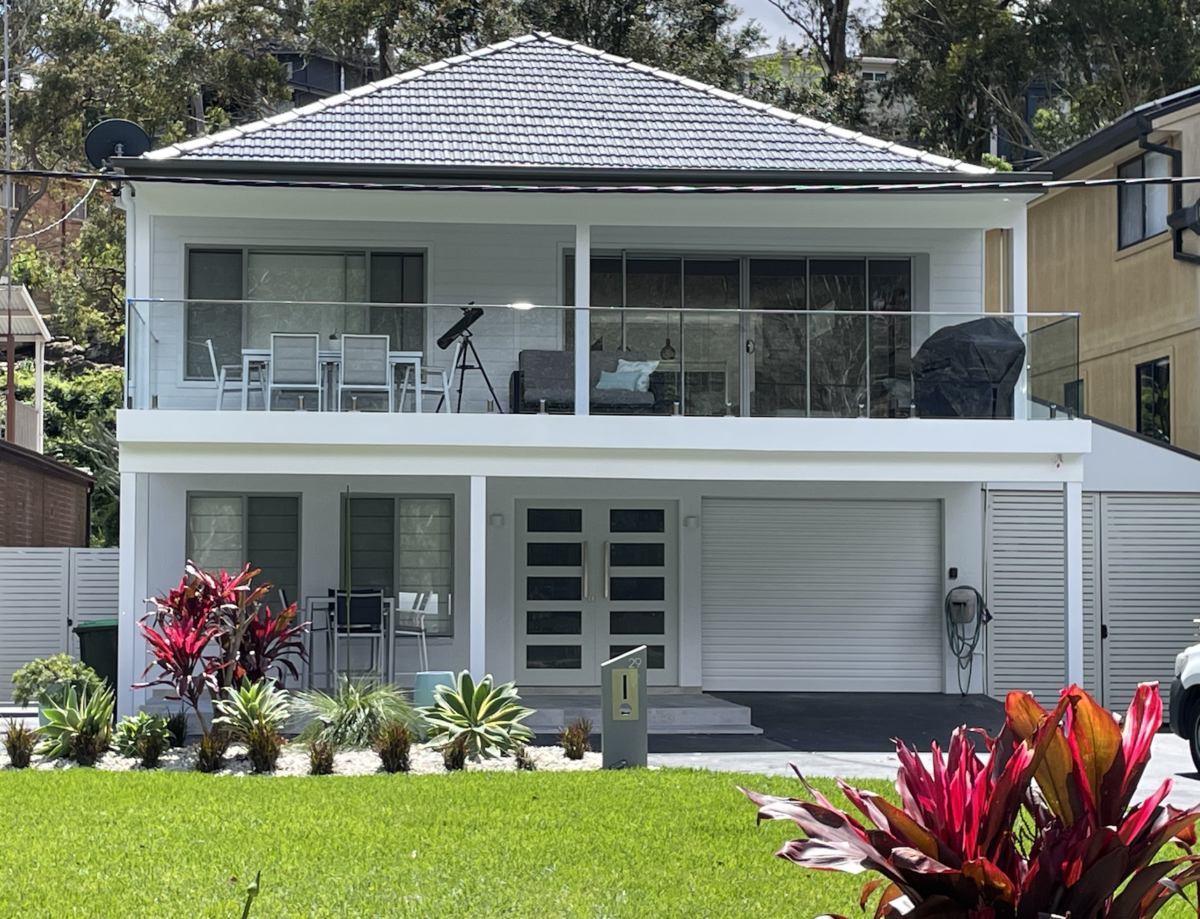 Exterior repaint for modern two-story white house with glass balcony.