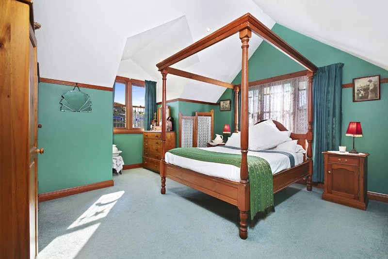 Interior bedroom repaint, bold colours, bedroom painted in green. high-pitched angled roof repaint in a country-style home. 