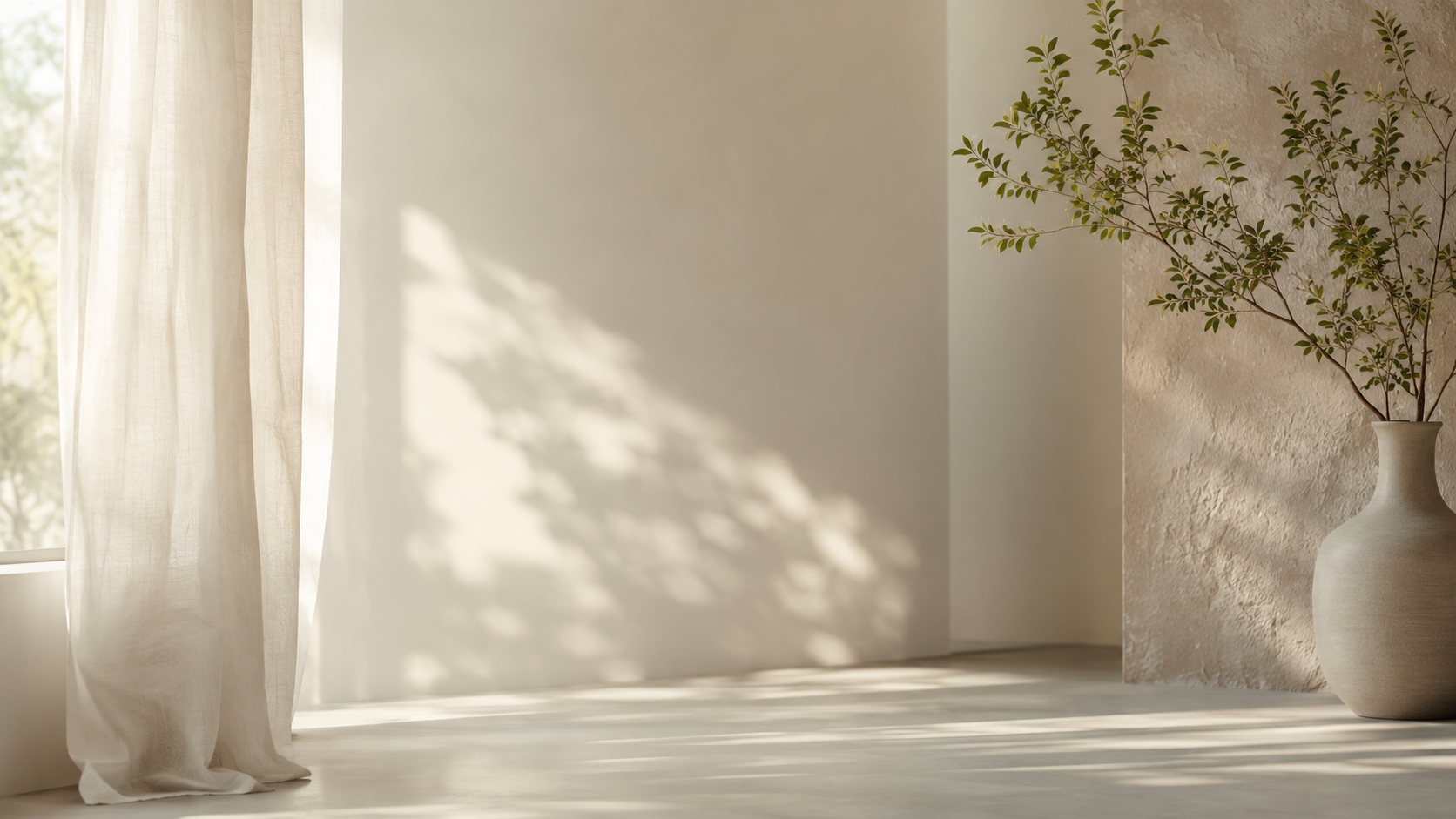 Sunlight streaming through sheer white curtains onto a minimalist room with a textured beige wall and a large ceramic vase with green foliage.