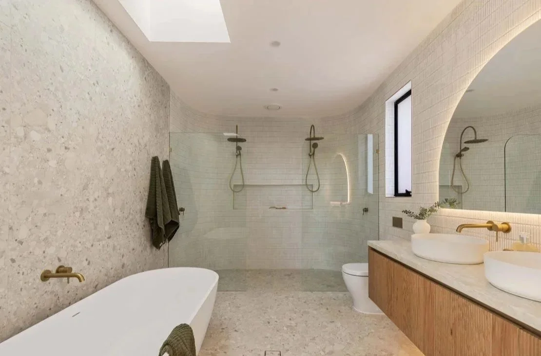 Modern bathroom with a freestanding bathtub, double vessel sinks, and a walk-in shower with dual showerheads.