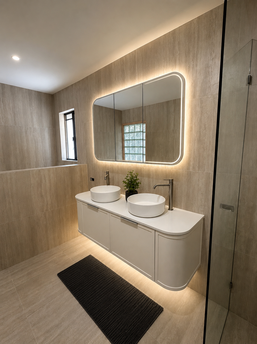 Modern bathroom renovation on the Gold Coast by Ben Built Homes featuring double vanity round basins and nib wall to open the space, feature lighting under the vanity