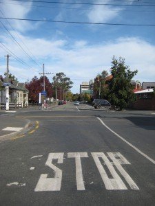Small town intersection with the word “stop” lettered on its black asphalt.